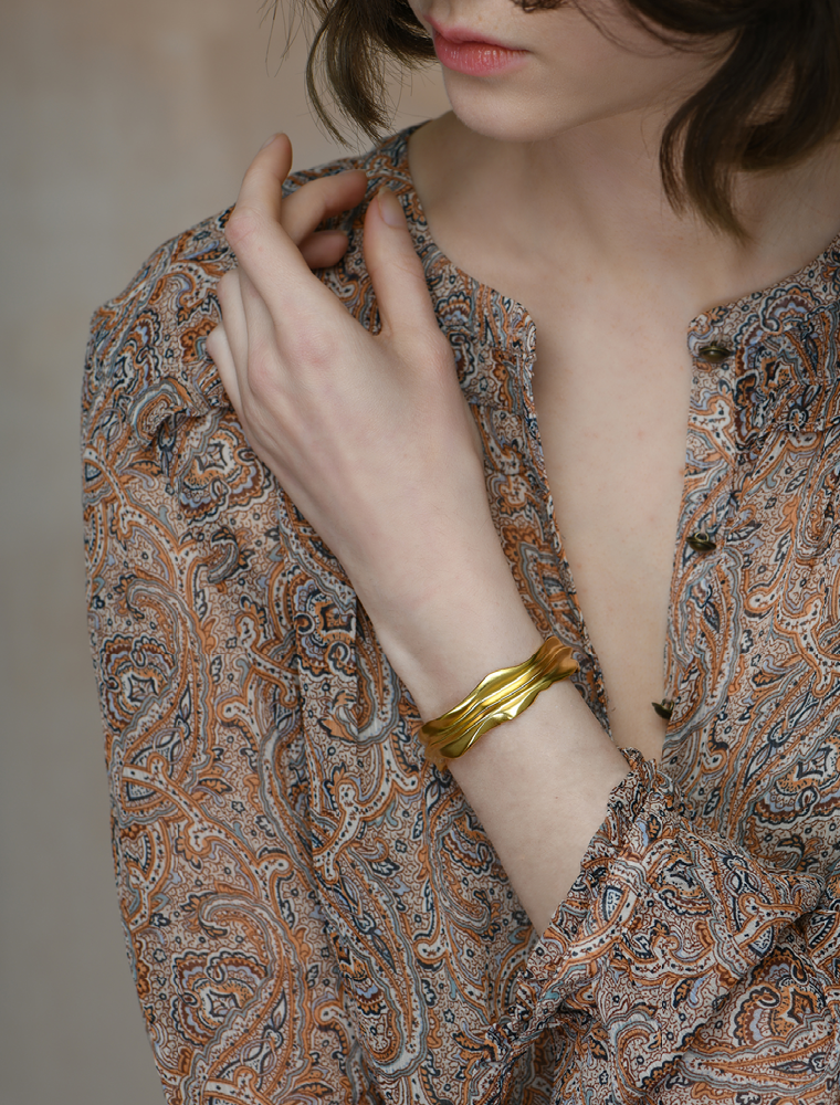 A model wears a gold vermeil bangle with smooth valleys and edges.