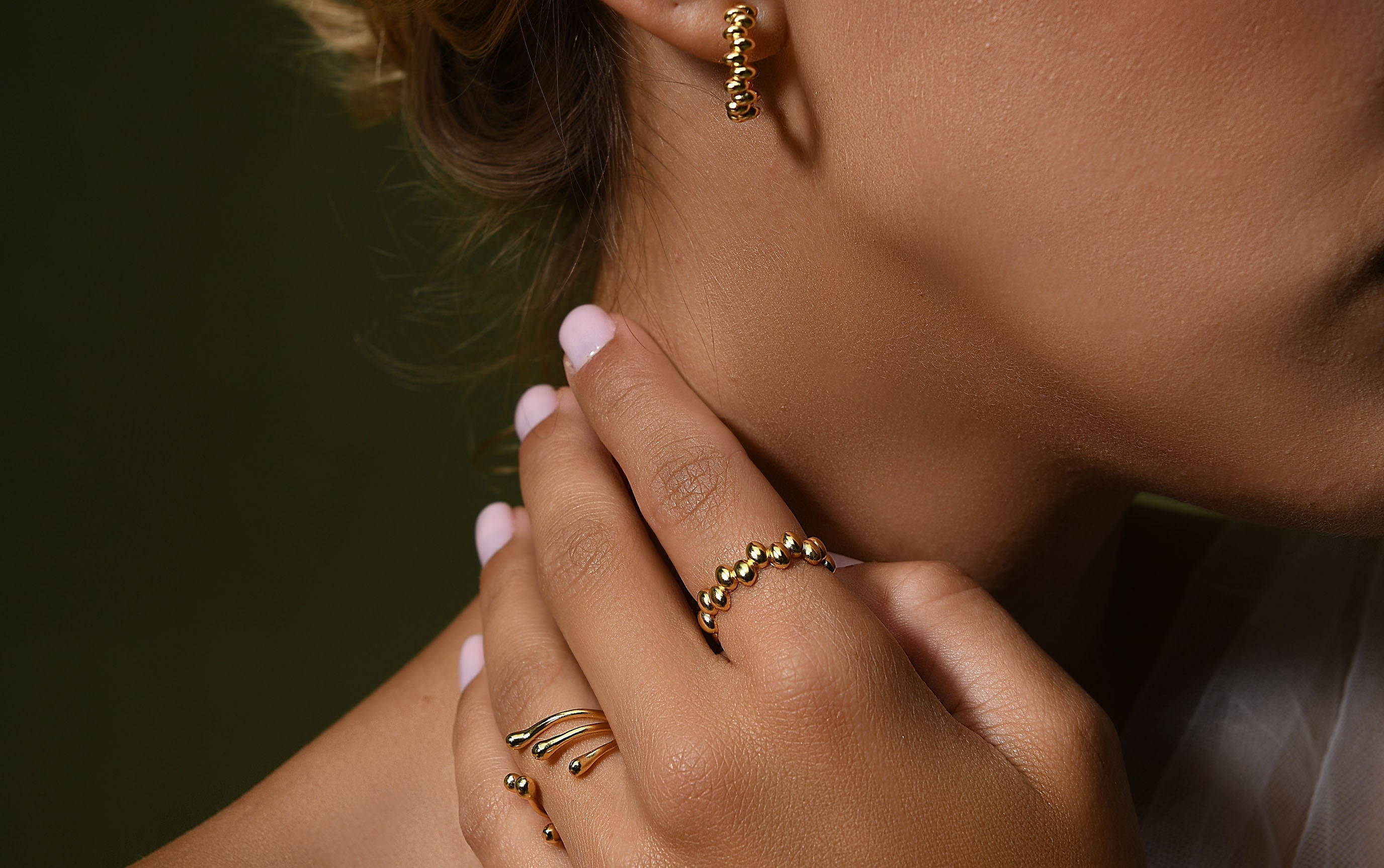a close up of a female hand wearing delicate gold vermeil silver rings resemblance of liquid fluidity