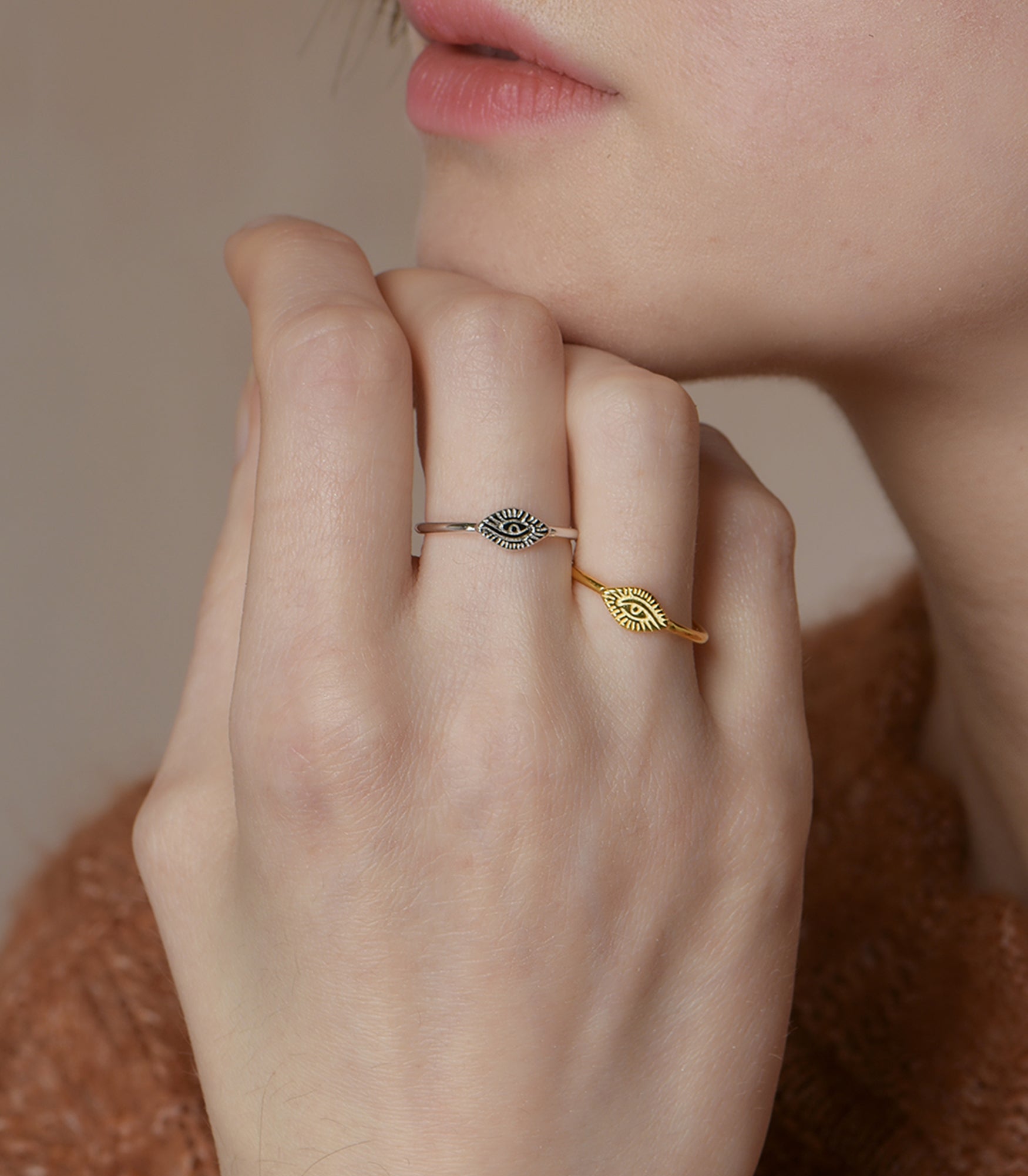 A model wears two rings in silver and gold with an open band design and the eye of providence featuring at the front of the ring.