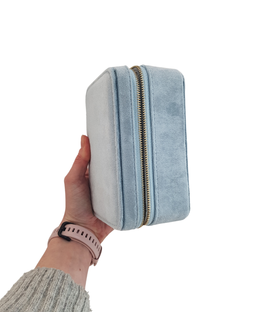 A light blue, velvet jewellery storage box. The box is rectangular with a zip fastening.