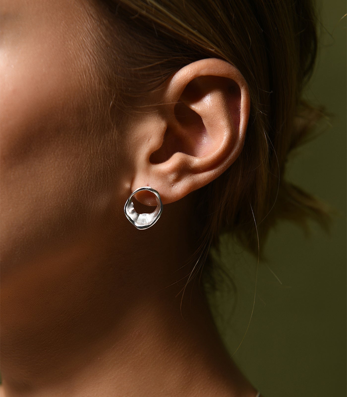 A sterling silver stud earring. The earring has an irregular shape, similar to the movement of flowing water.