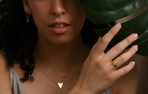 a female model wearing gold modern jewellery earrings ring