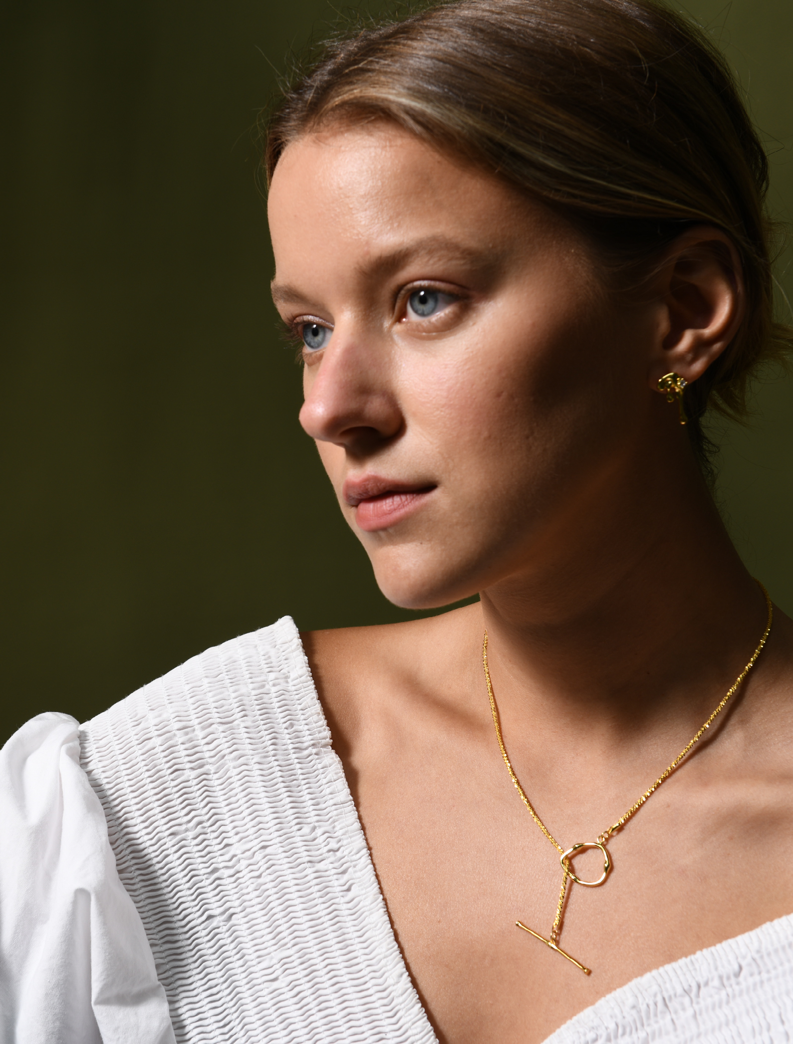 A female model wearing a gold vermeil necklace with a toggle clasp sat at the front. The women also wears gold vermeil earrings.