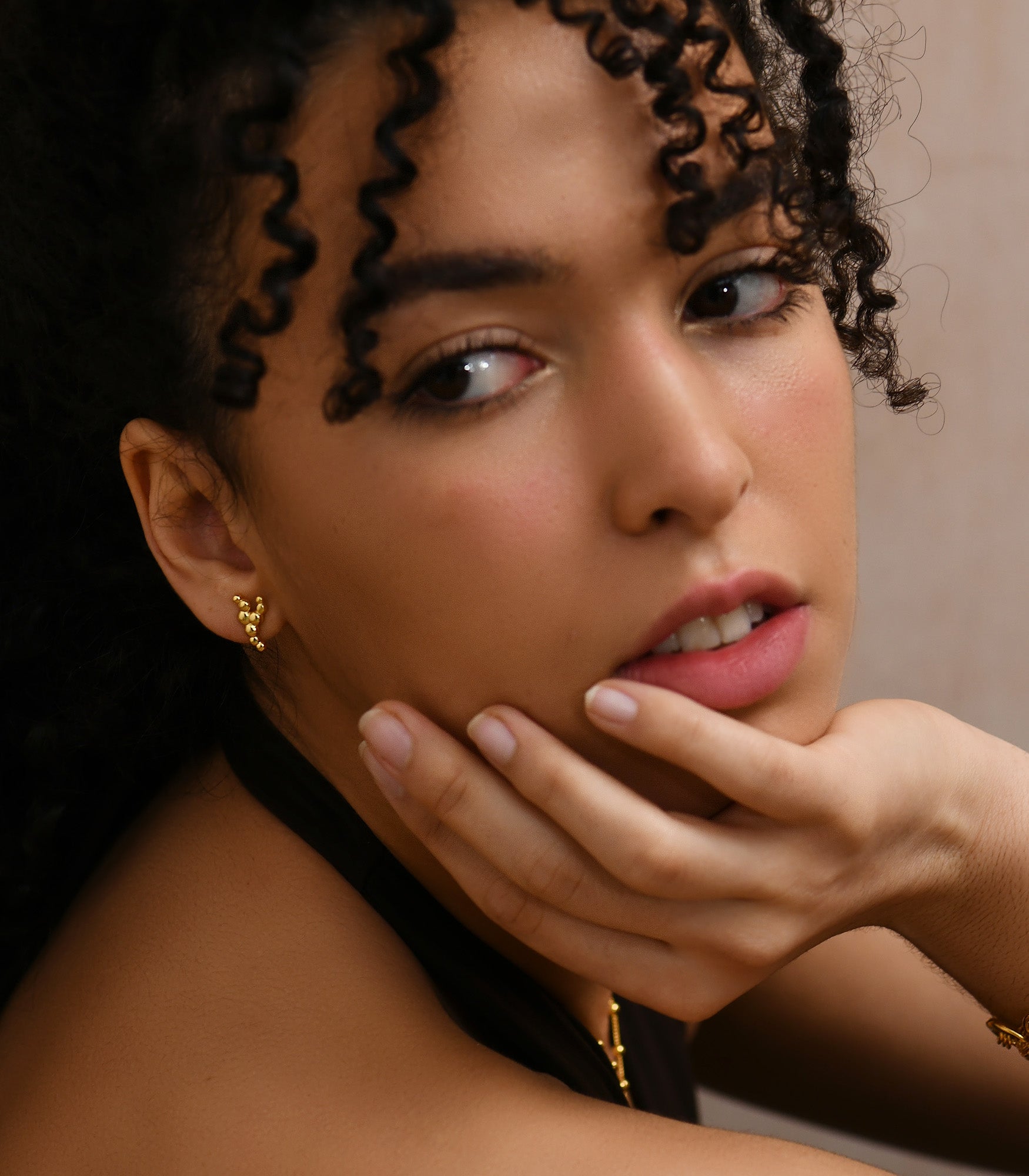 a close up photo of a pretty female model face, wearing a gold plated silver stud earrings which is reminiscent of bubbles