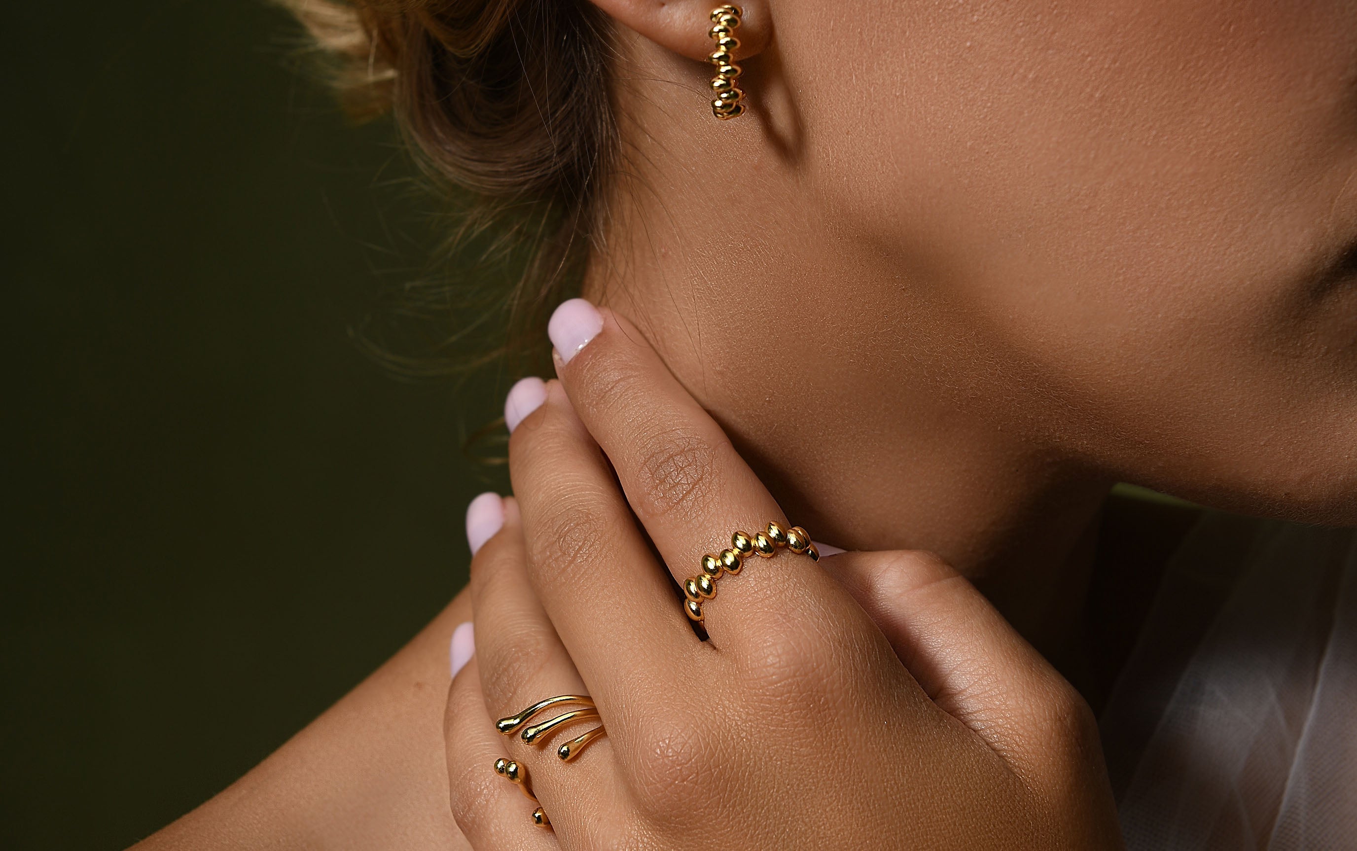 a close up of a female hand wearing delicate gold vermeil silver rings resemblance of liquid fluidity   