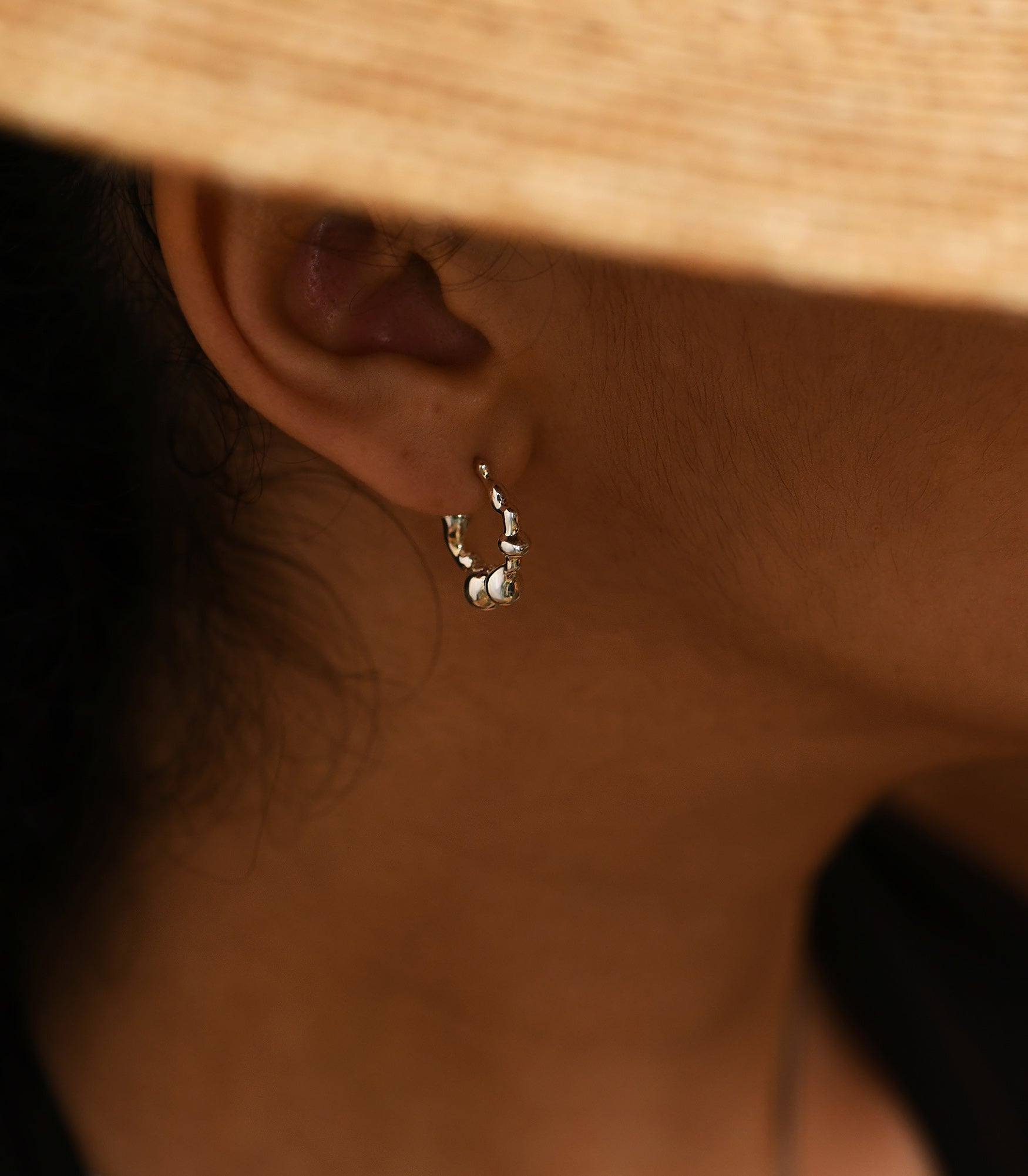 a pair of polished silver earrings featuring bubble shapes on a female model