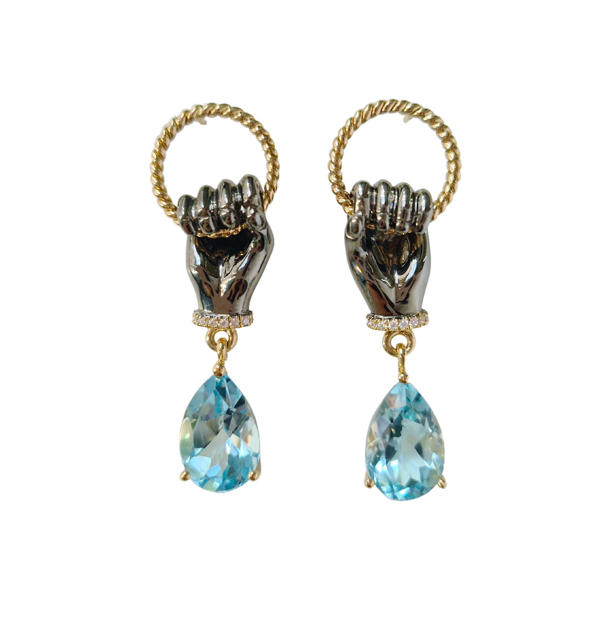 A pair of gold earrings. The earrings have 2 small hoops with hands held on and a blue topaz dangling from the wrists of the hand.
