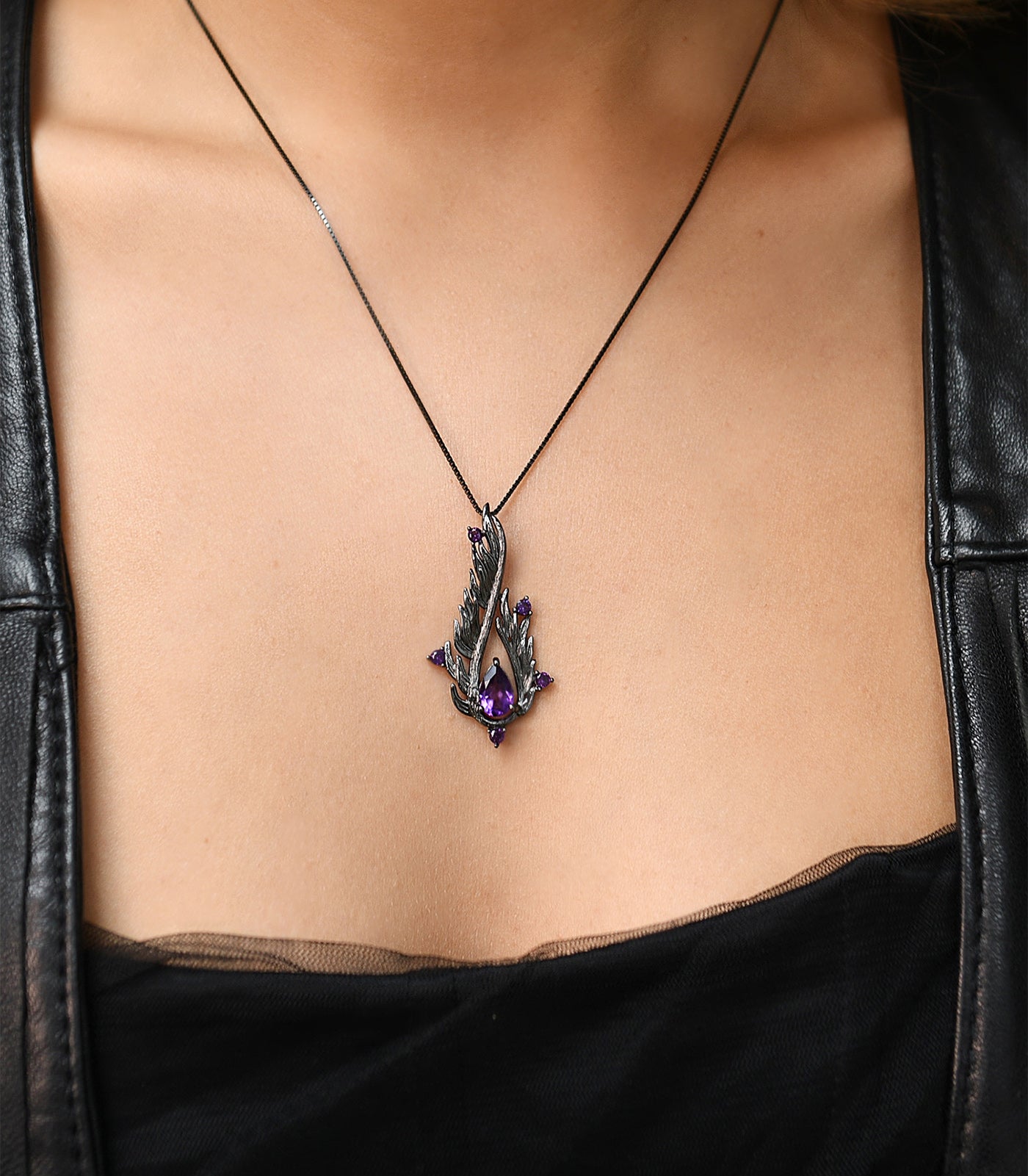 An oxidised sterling silver necklace with a teardrop shaped pendant. The necklace has purple amethyst stones.