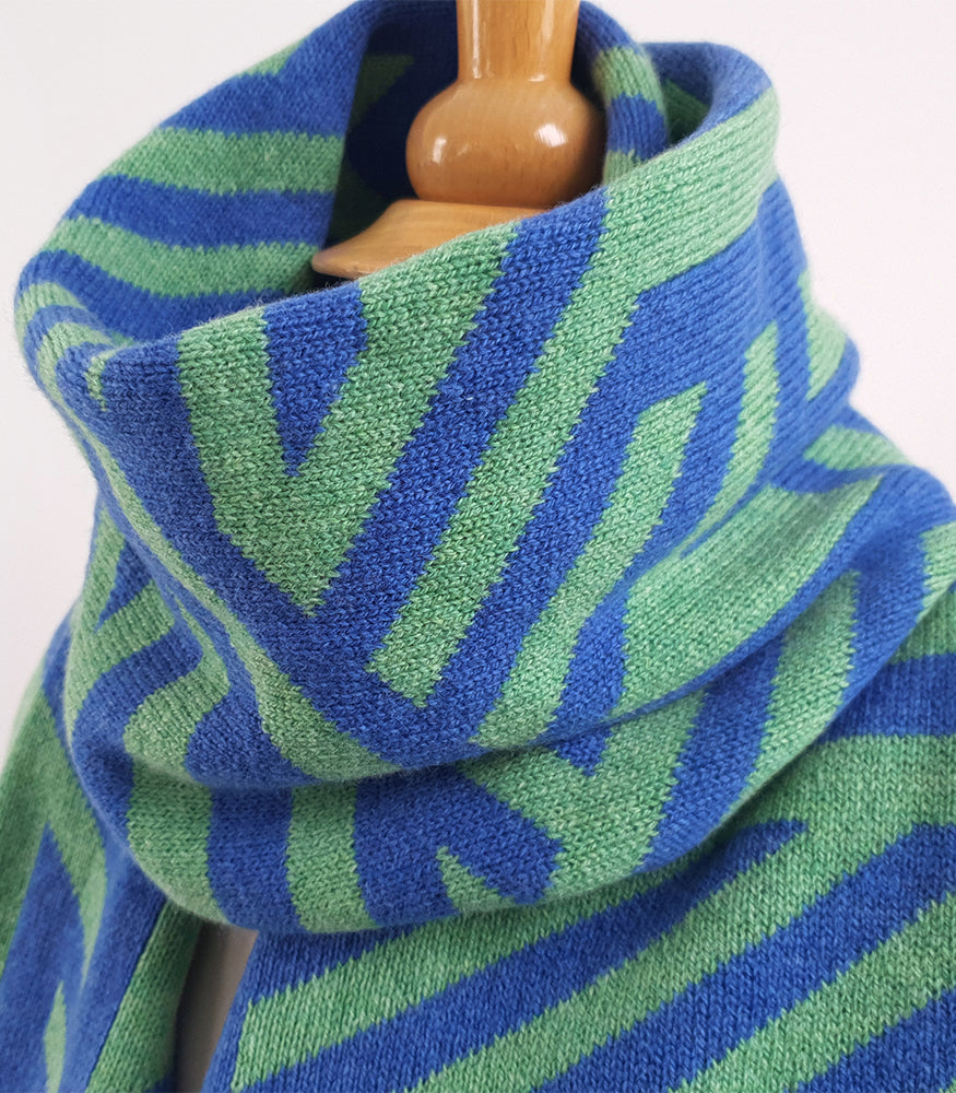 A close up of a knitted lambswool scarf. The scarf is expertly crafted with a blue and green crosswise pattern.