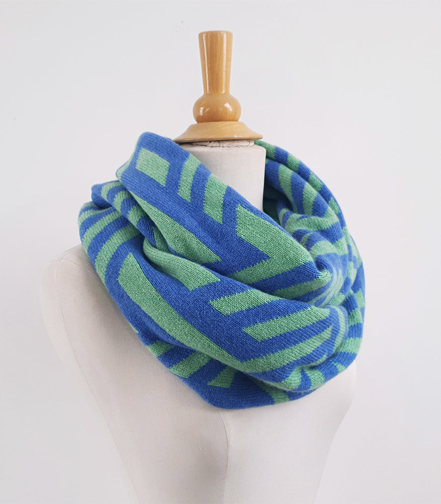 A blue and green knitted snood. The snood is handmade with lambswool and has a geometric crosswise pattern