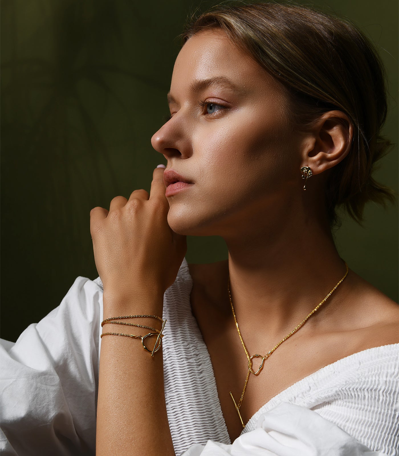 A lady wearing a gold vermeil chain necklace with a toggle clasp, paired with a gold vermeil bracelet and earrings. 