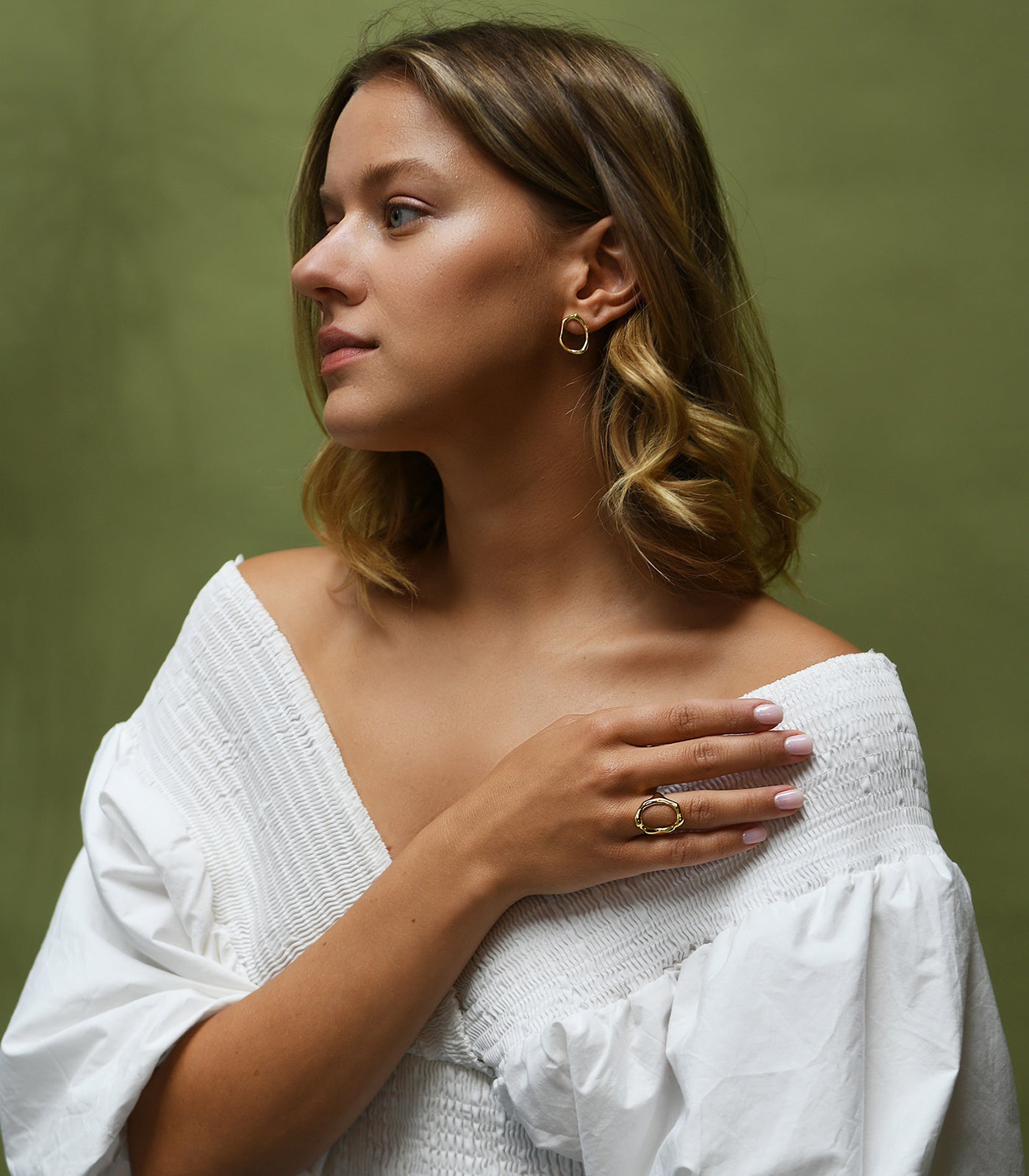 A model wearing a gold vermeil, irregularly shaped circle stud earring.