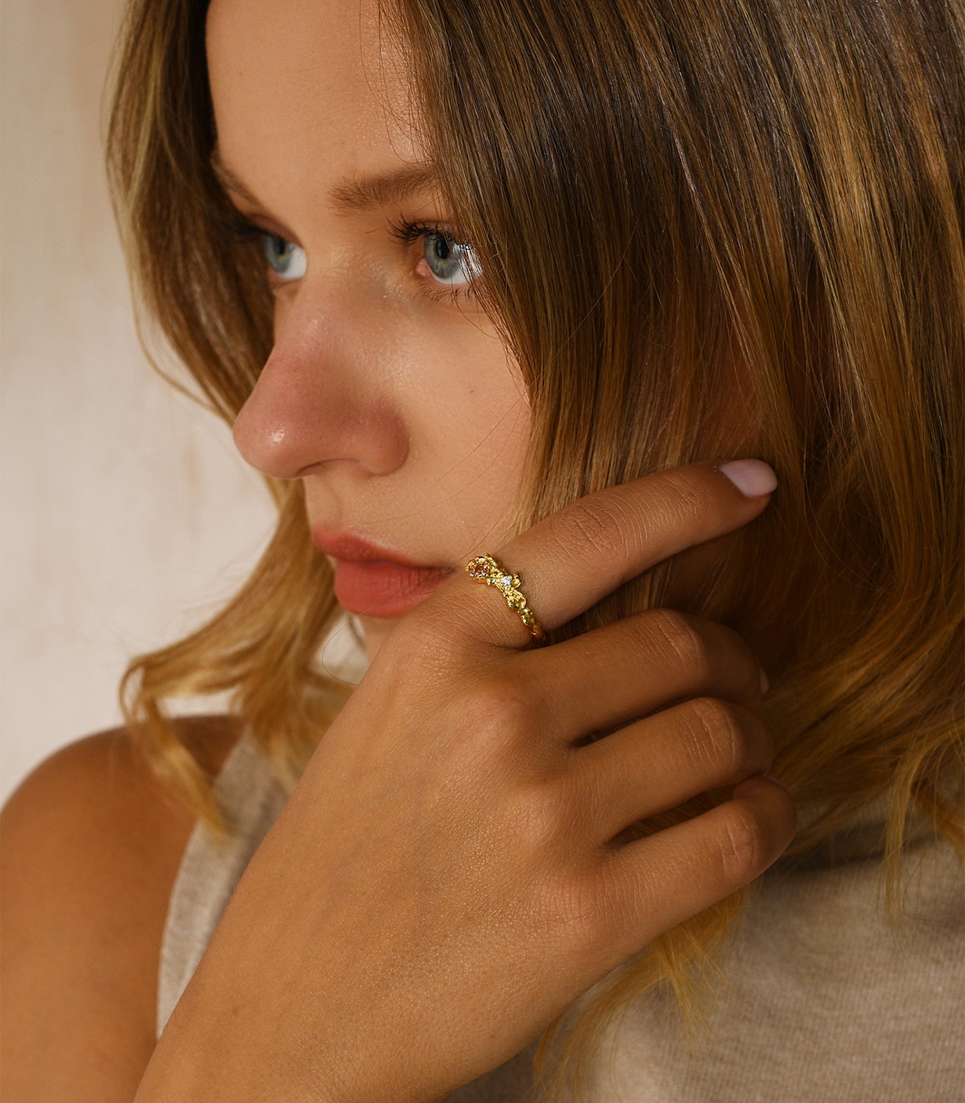 A model wears a gold vermeil ring. The ring features a textured design with a champagne gold gemstone.