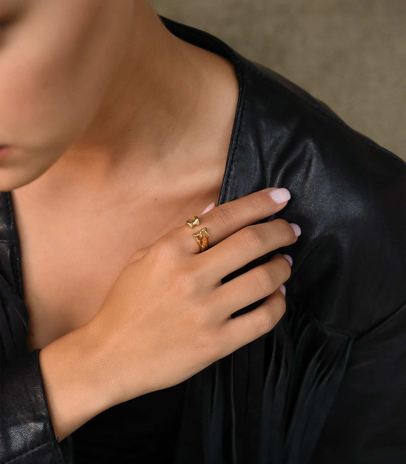 A model wears a gold vermeil ring with a bone shape. The ring has an open band design.