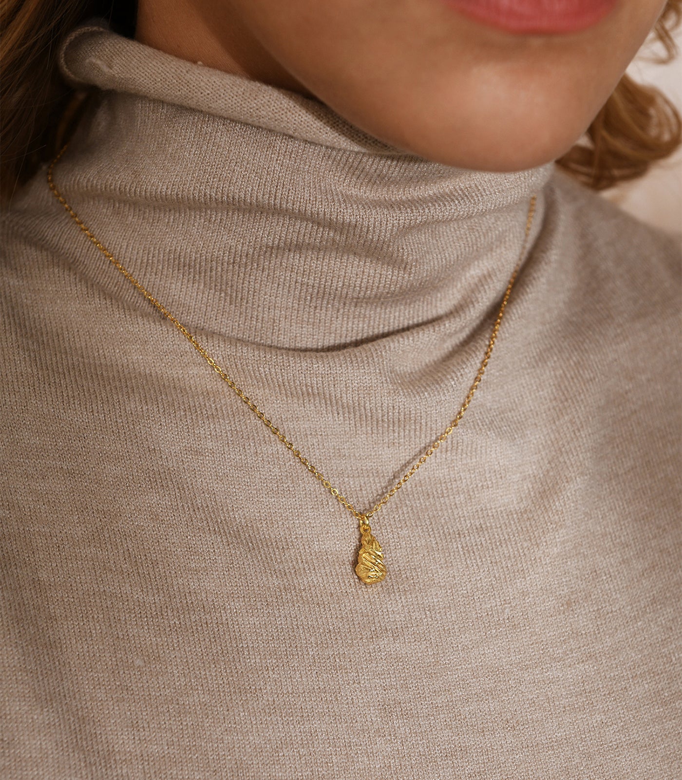 A model wears a gold vermeil necklace with a nugget pendant.