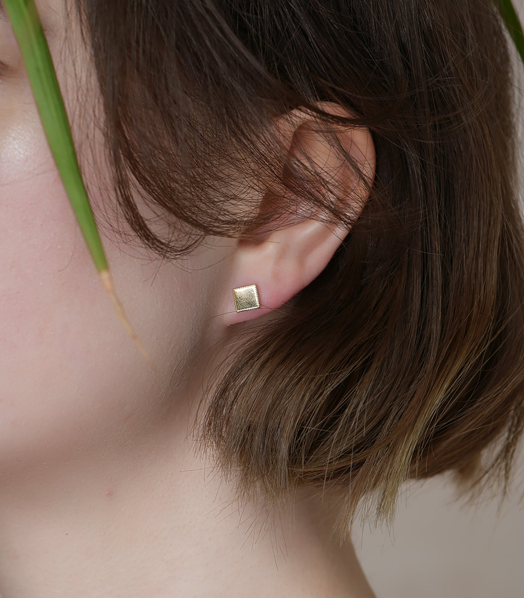A model wears a gold vermeil, square shaped stud earring.