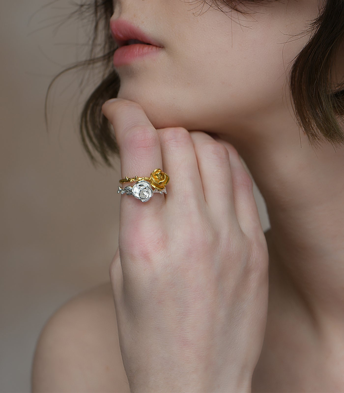A model wears a gold vermeil ring with a thorn detail on the band. The ring also has a rose feature on the top of the band.