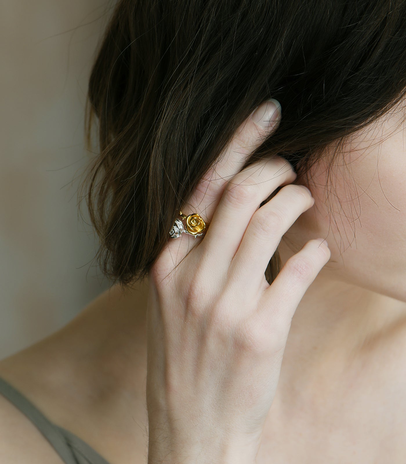A model wears a gold vermeil ring with a thorn detailing on the band and a rose design on the top of the ring.
