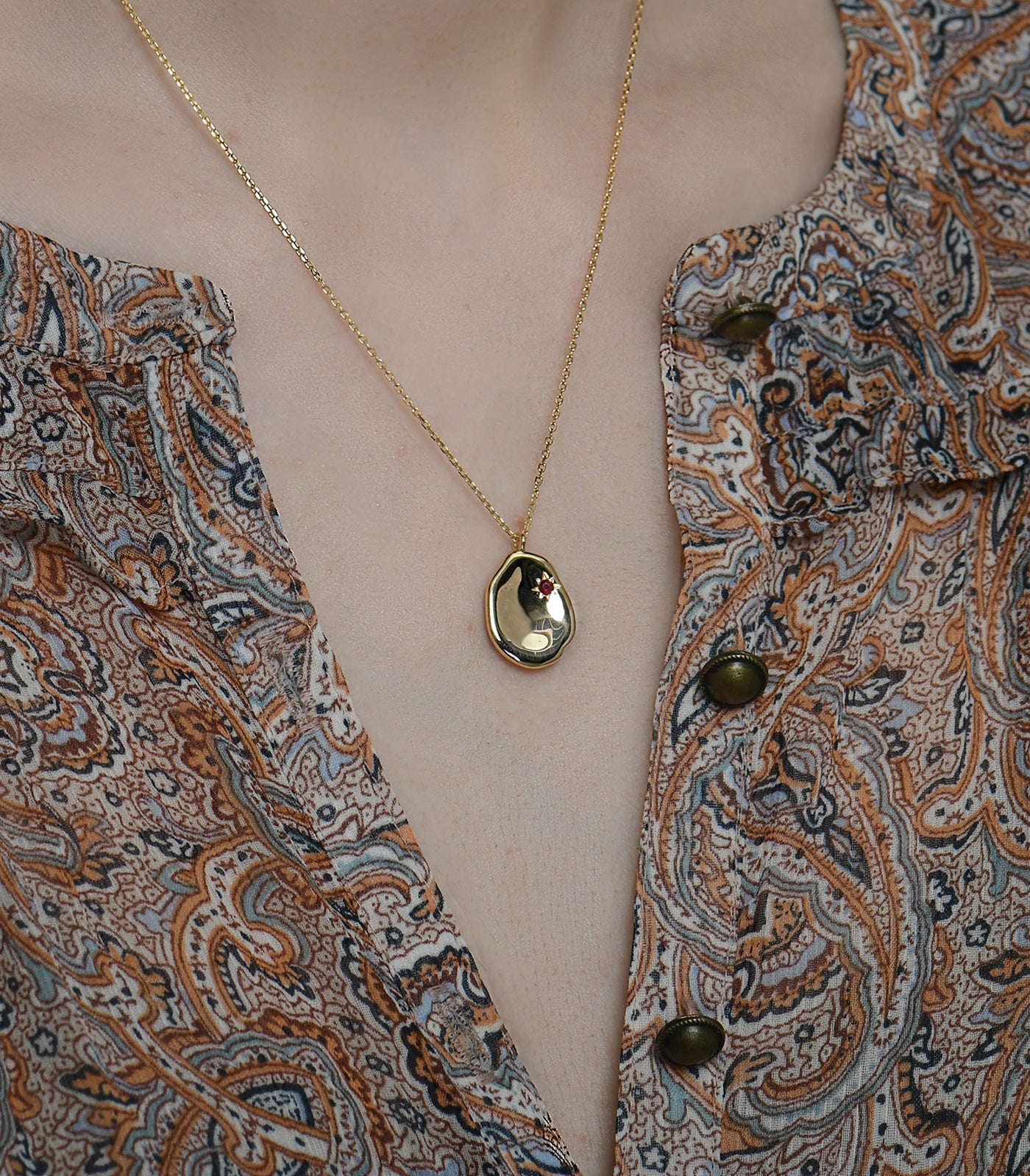 A gold vermeil necklace with a ruby stone pebble pendant