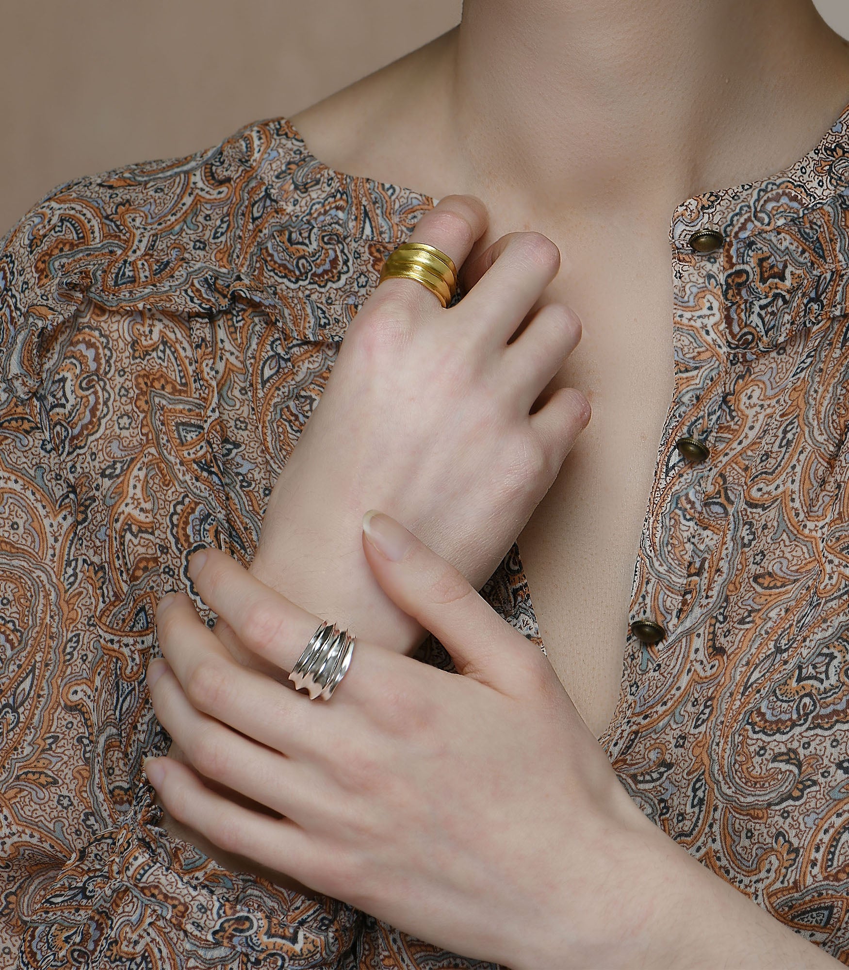 A model wears a gold vermeil ring paired with a sterling silver ring. Both rings have the same design with smooth valleys and ridges.