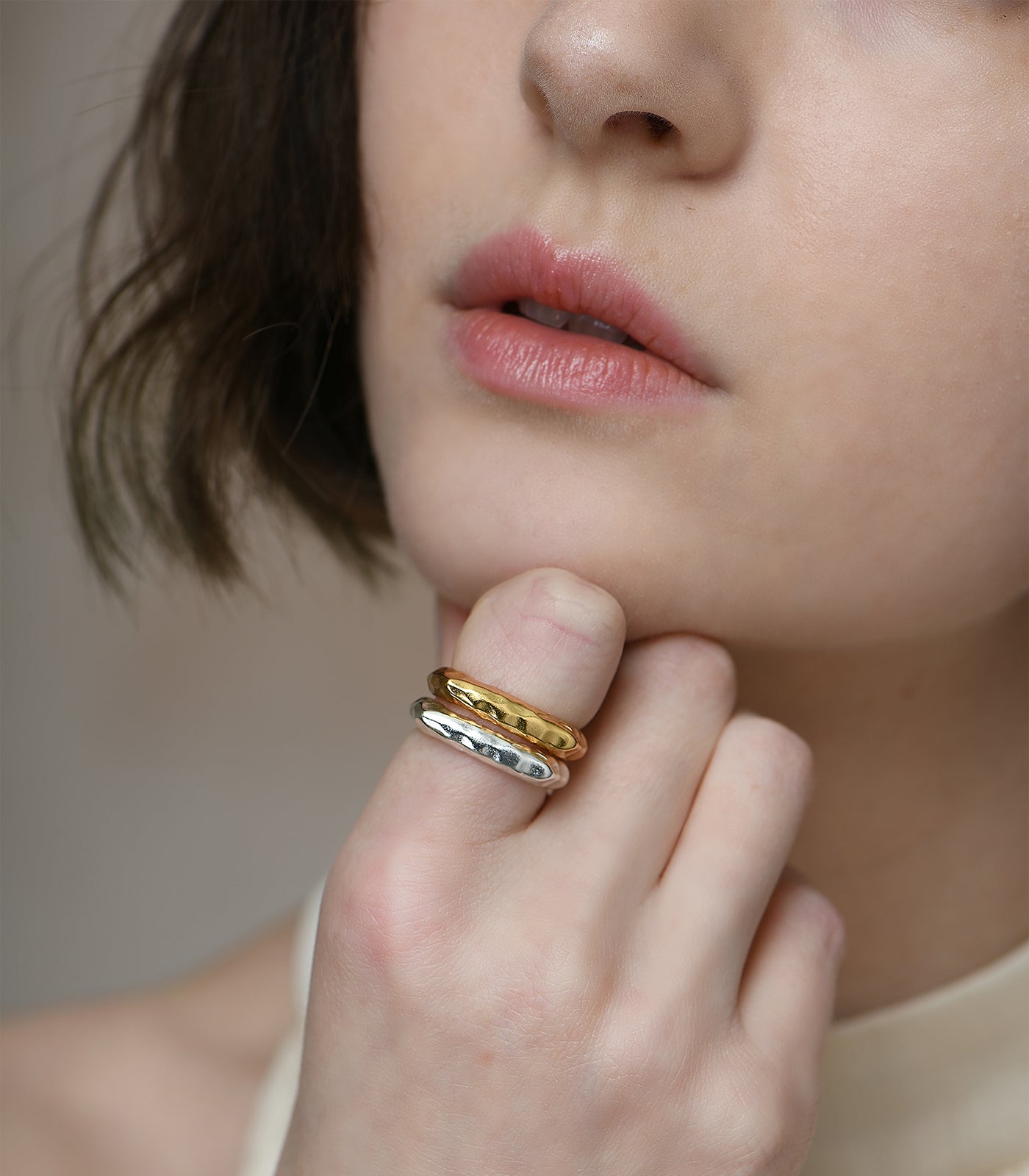 A gold vermeil ring and sterling silver ring on a model. Both rings have a plateau open band design.