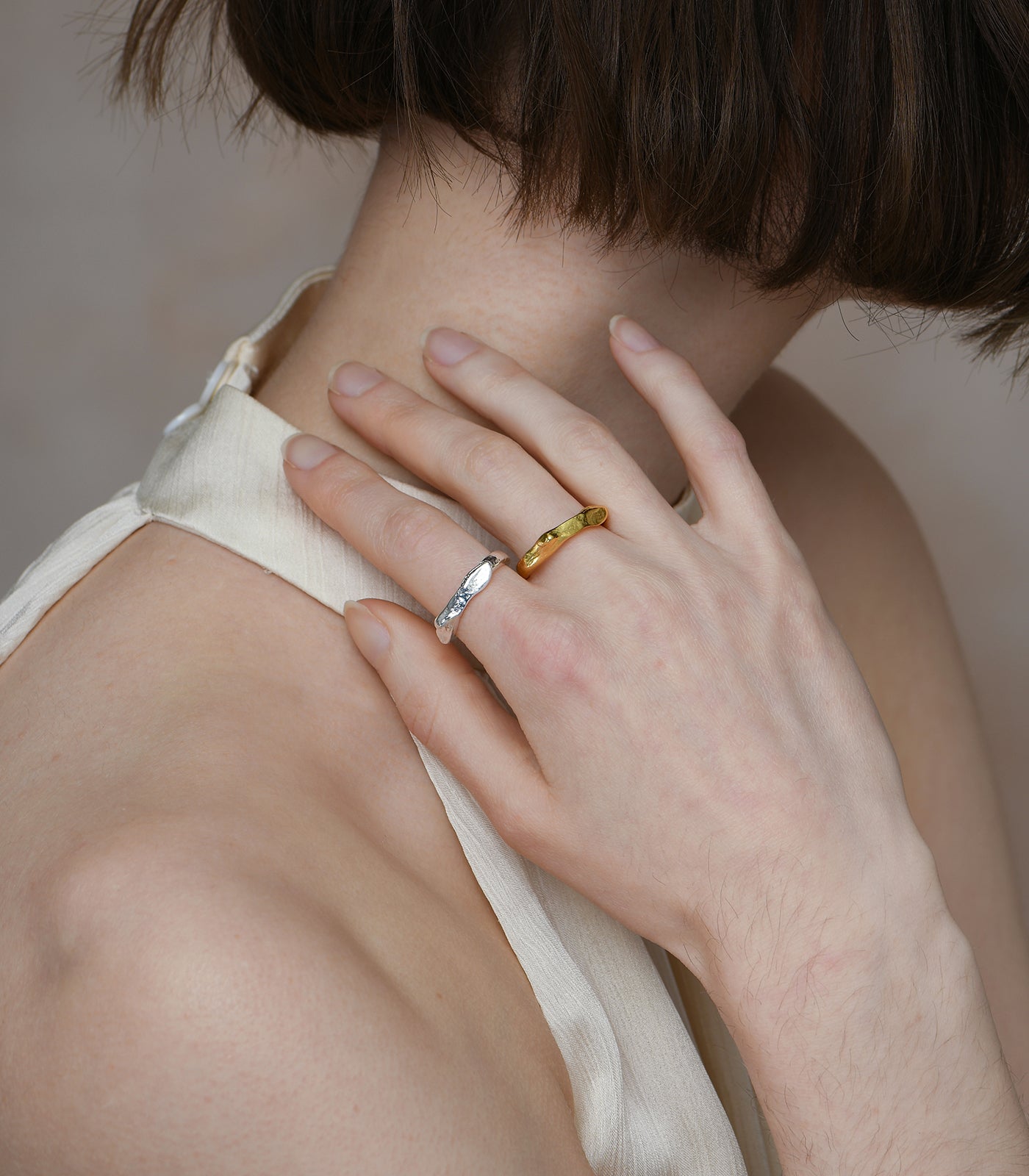 A model wears 2 rings, a sterling silver and gold vermeil ring. Each ring has a chunky band and organic rocky texture.