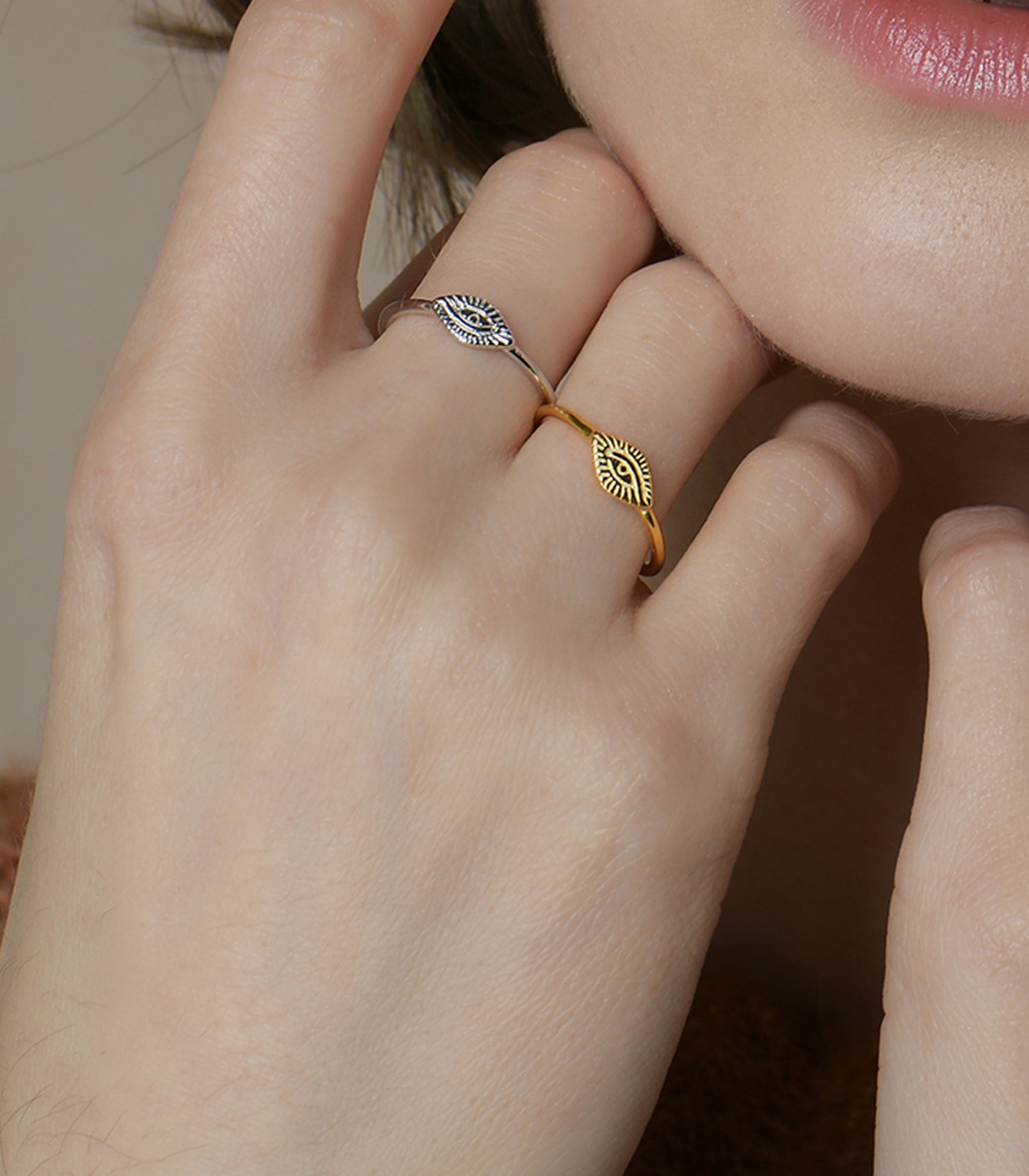 A model wears two rings in silver and gold with an open band design and the eye of providence on the front of the ring.