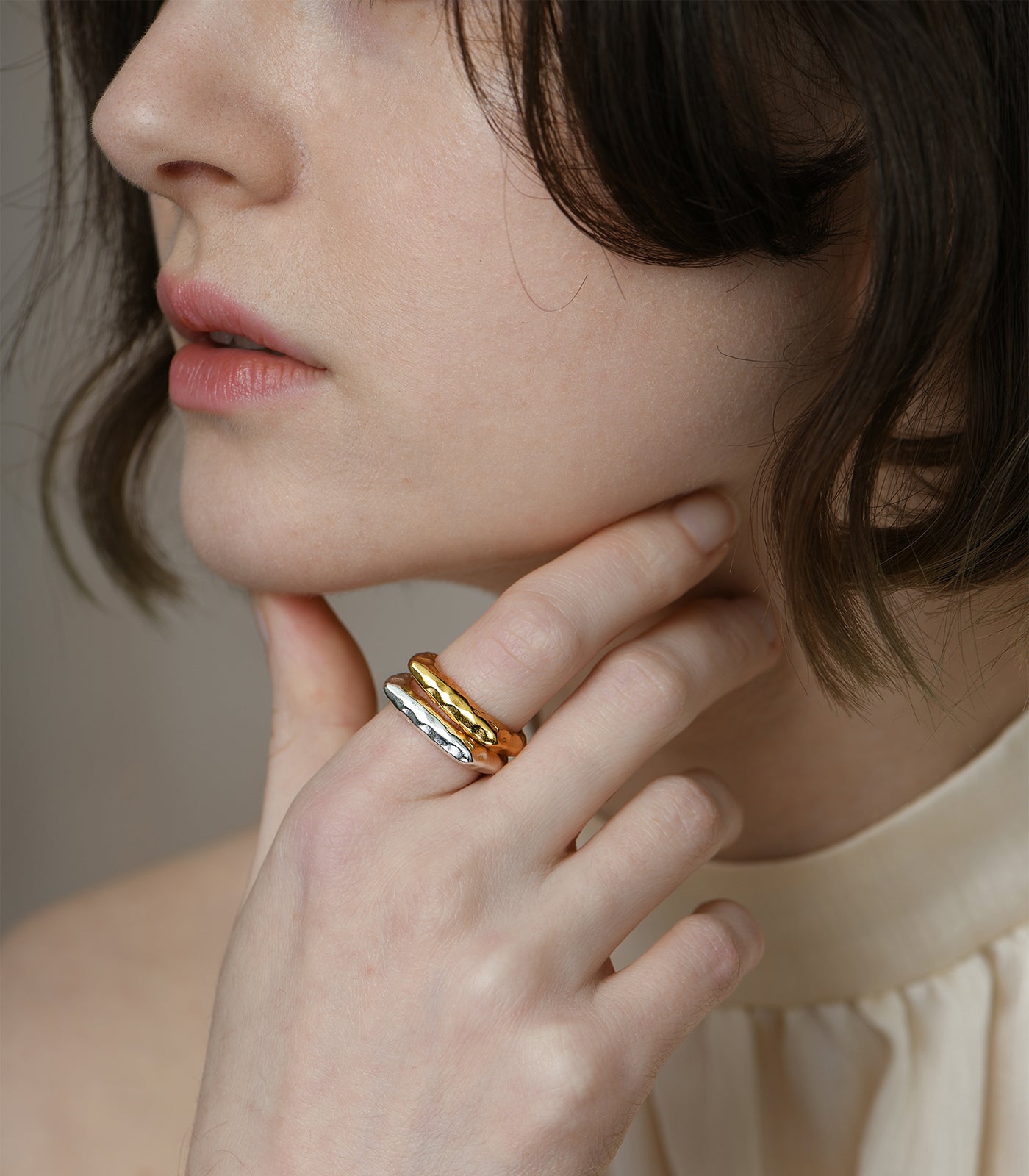 A model wears two open band, plateau rings. One ring is sterling silver while the other has a gold vermeil.
