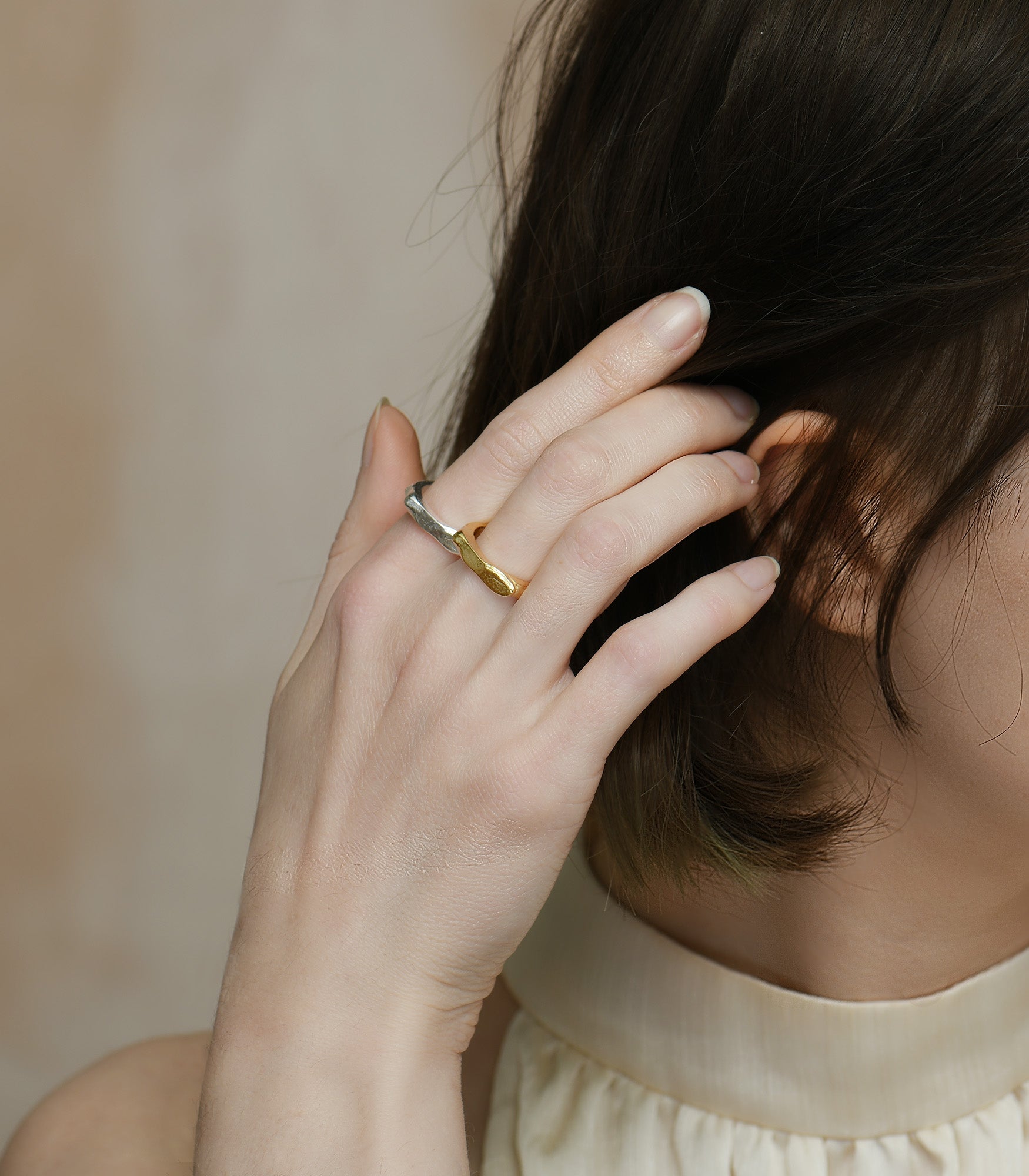 A model wears a sterling silver and a gold vermeil ring. Both rings have a chunky band and organic texture.