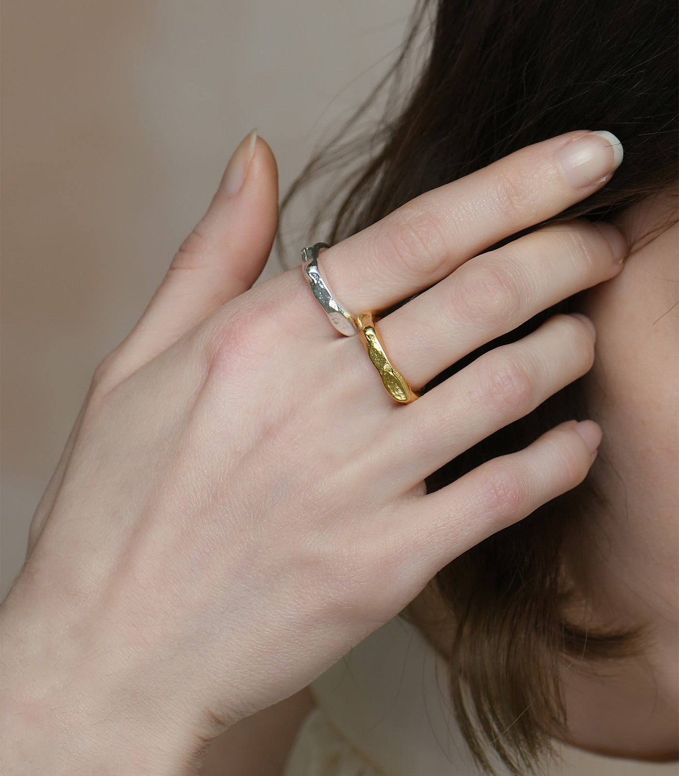 A model wears a sterling silver ring and gold vermeil ring with a chunky band and organic texture.
