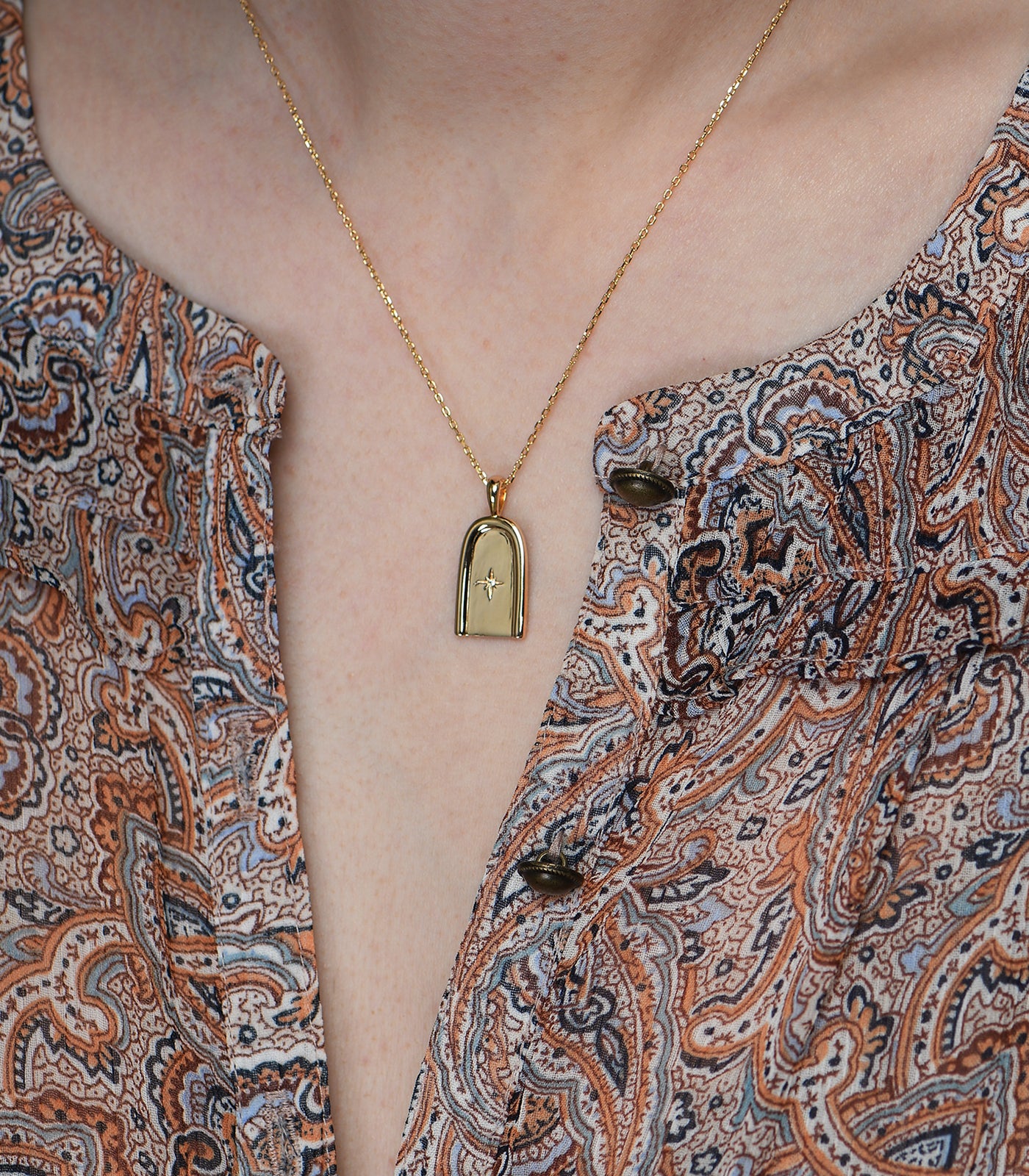 A gold vermeil necklace. The necklace has a dainty chain with an arch pendant.