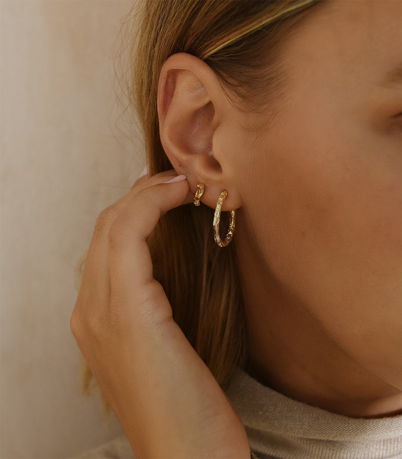 A gold vermeil textured hoop earring paired with a small gold vermeil stud earring resembling a tree branch.