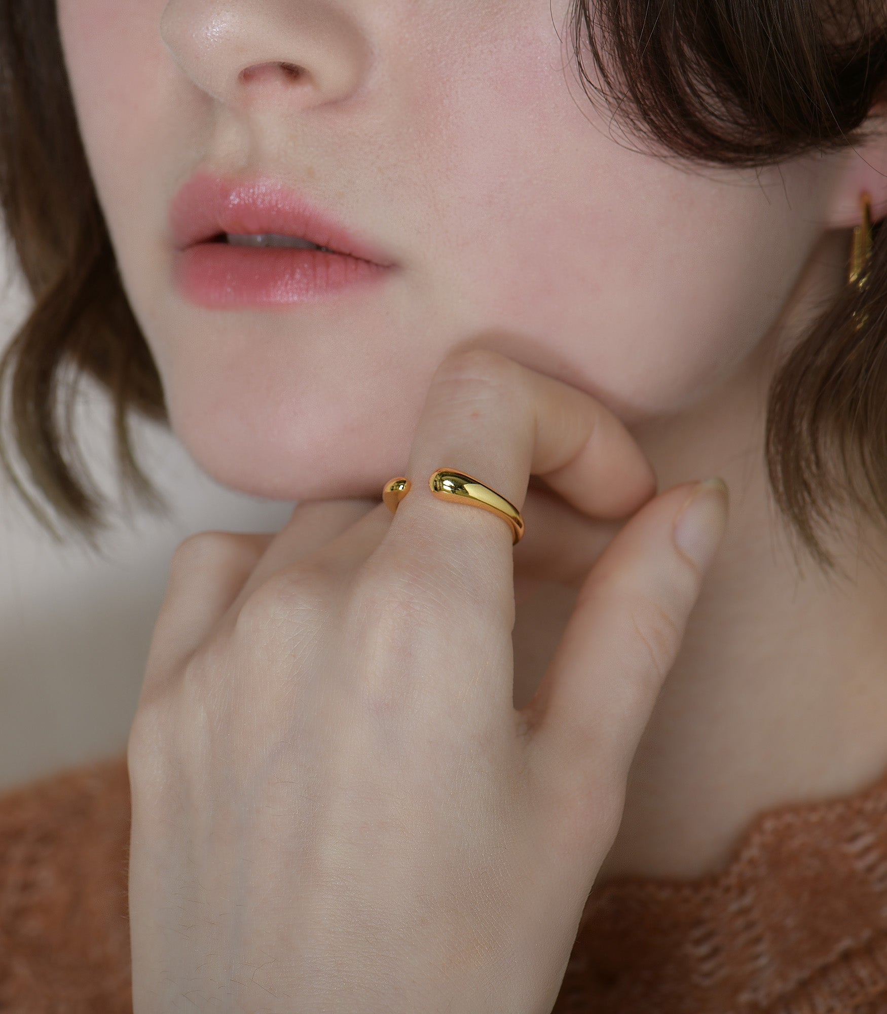 A model wears a polished, gold vermeil ring with a minimalistic design.