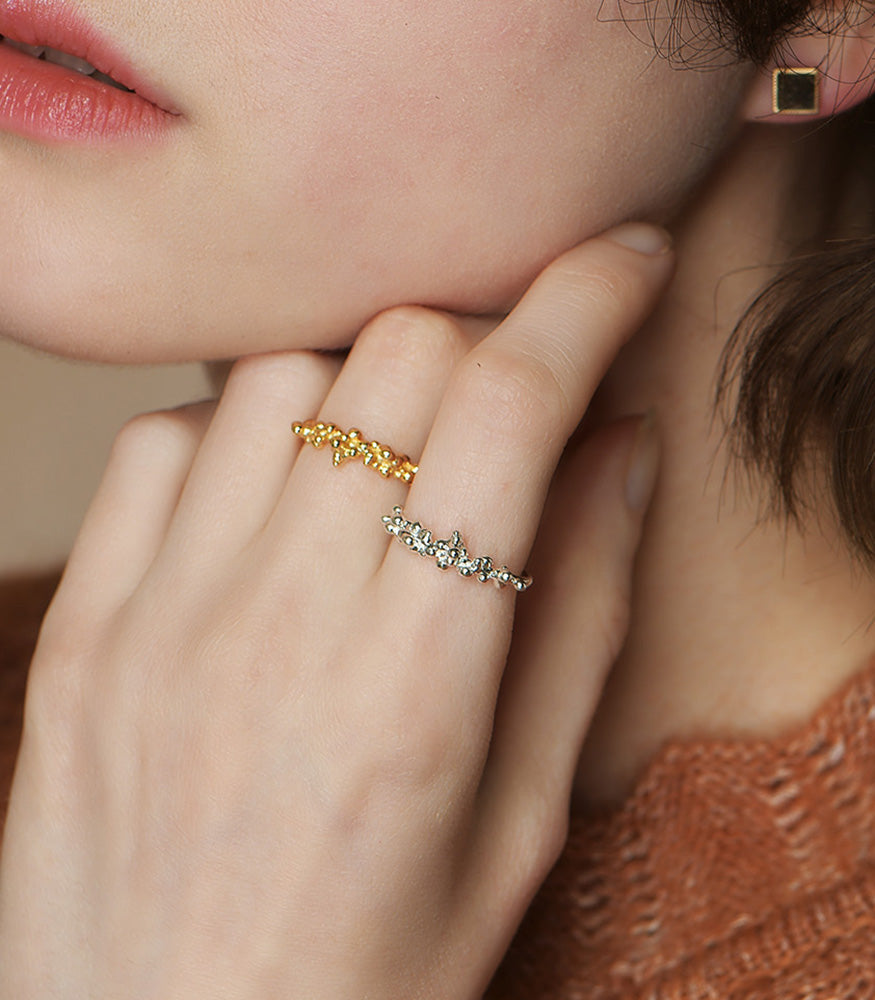 A model wears a gold vermeil and a sterling silver ring. Both rings have a bubble texture design.
