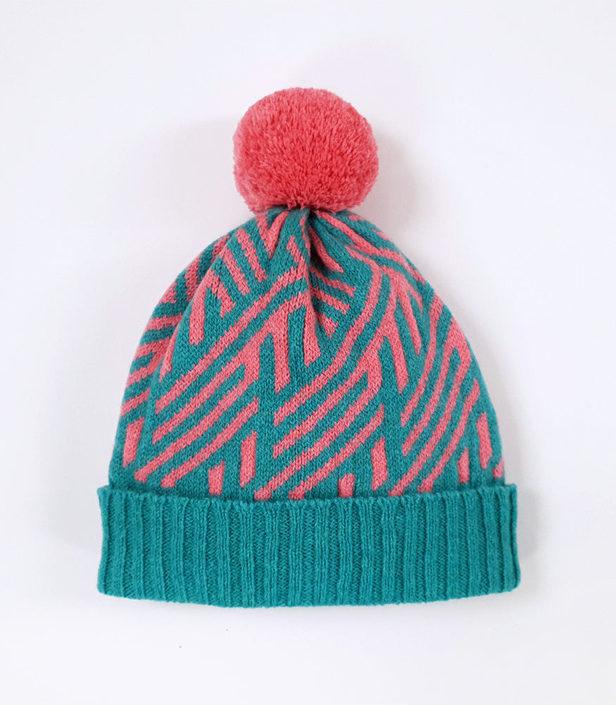A knitted bobble hat. The hat is blue and pink with a bold geometric crosswise pattern.