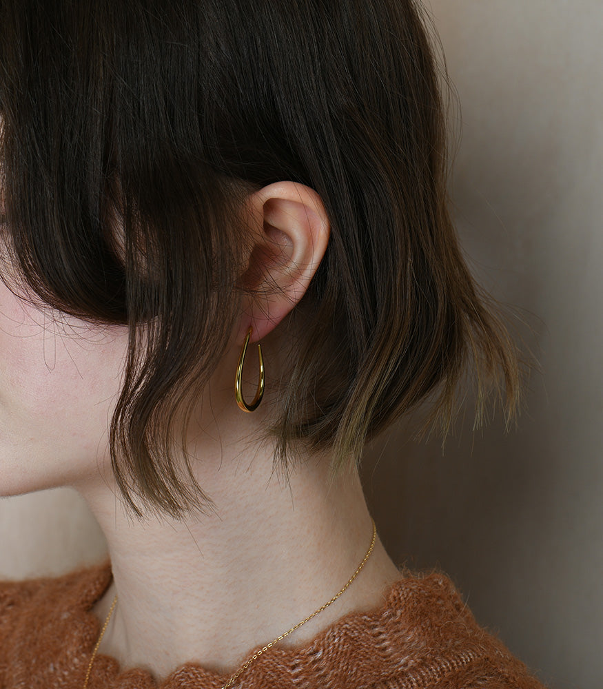 A pair of gold vermeil oval teardrop shape earrings on a model.