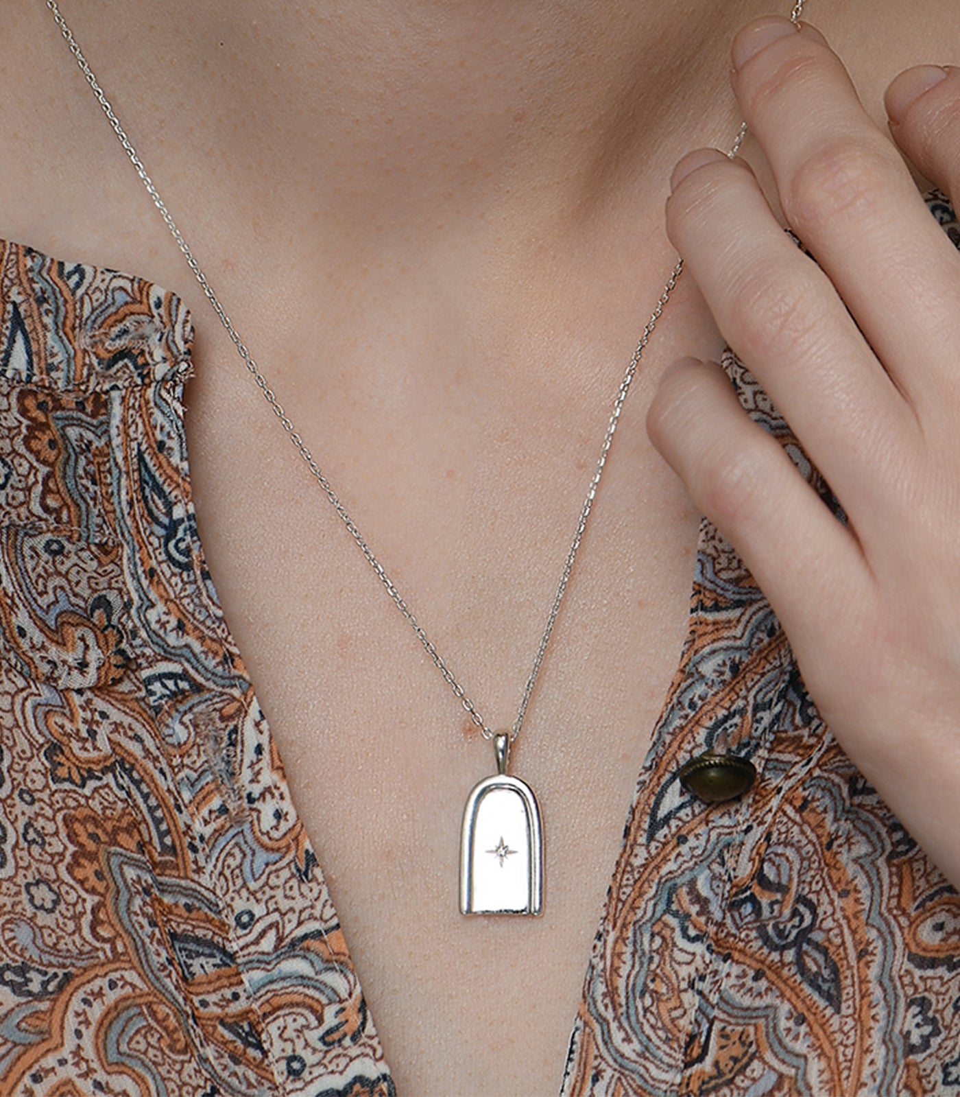 A sterling silver necklace with a dainty chain and an arch pendant.