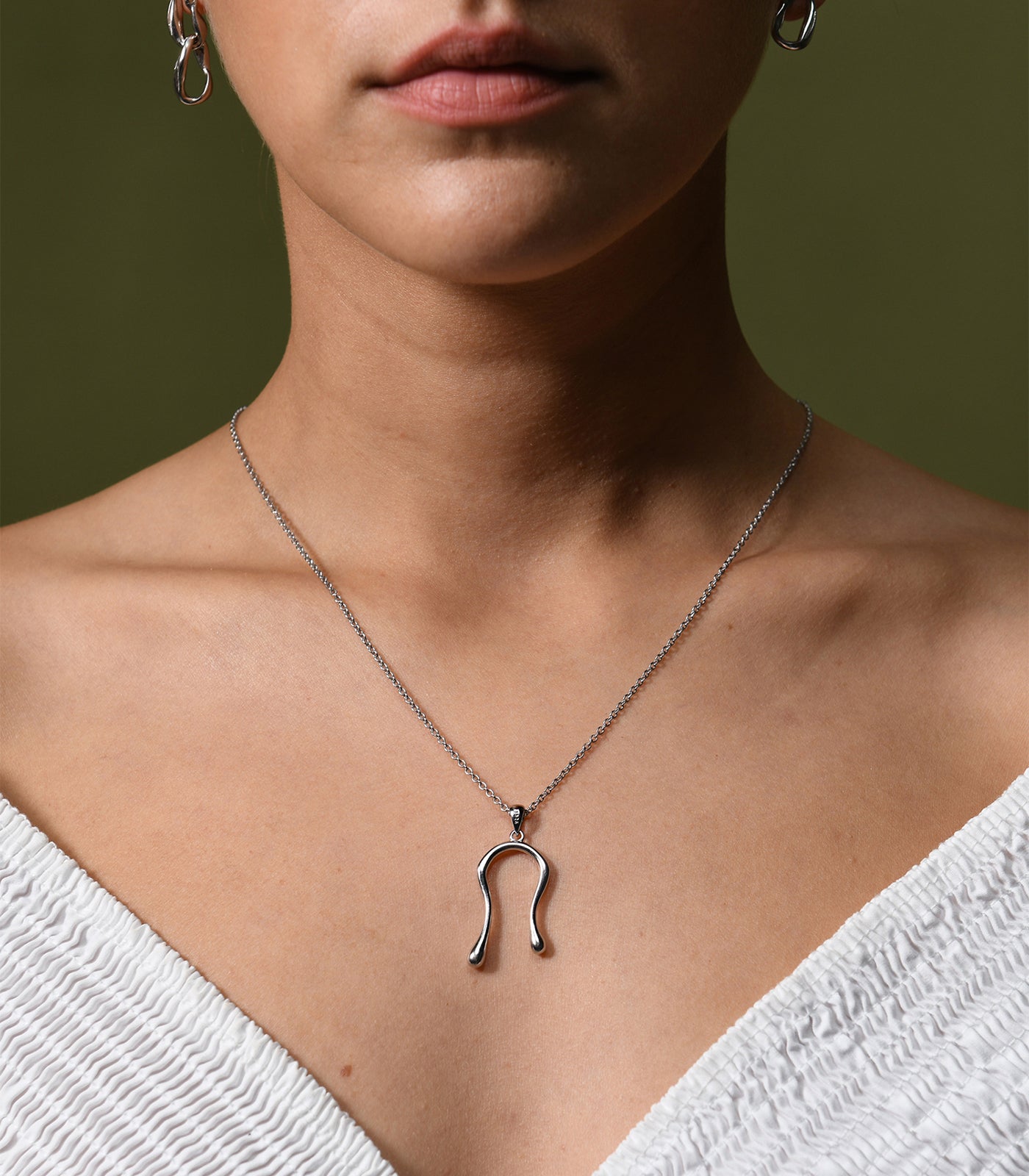 A model wears a sterling silver necklace with a liquid curve pendant. 