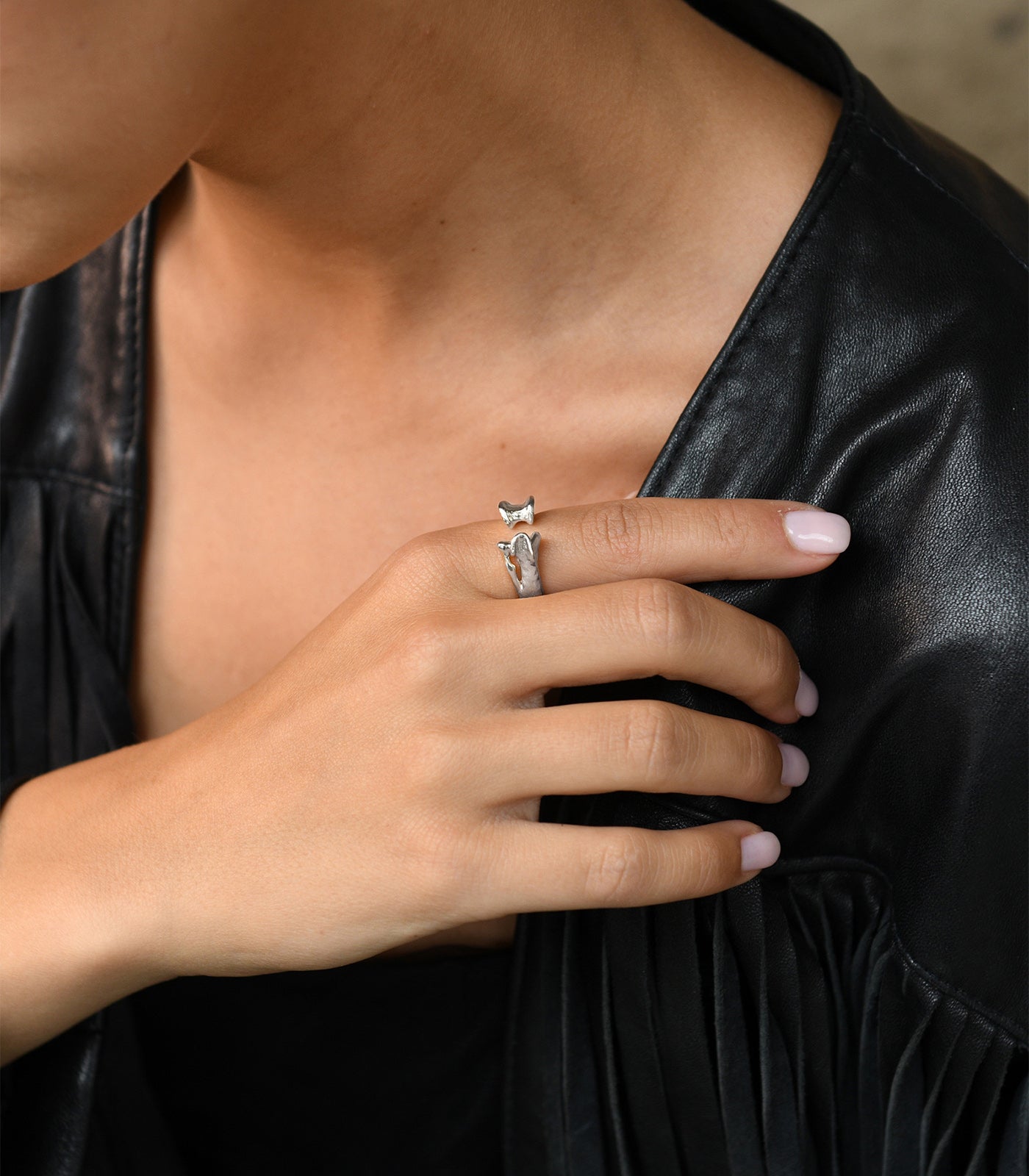 A model wears a sterling silver ring with an open band design. The ring also has a bone detailing.