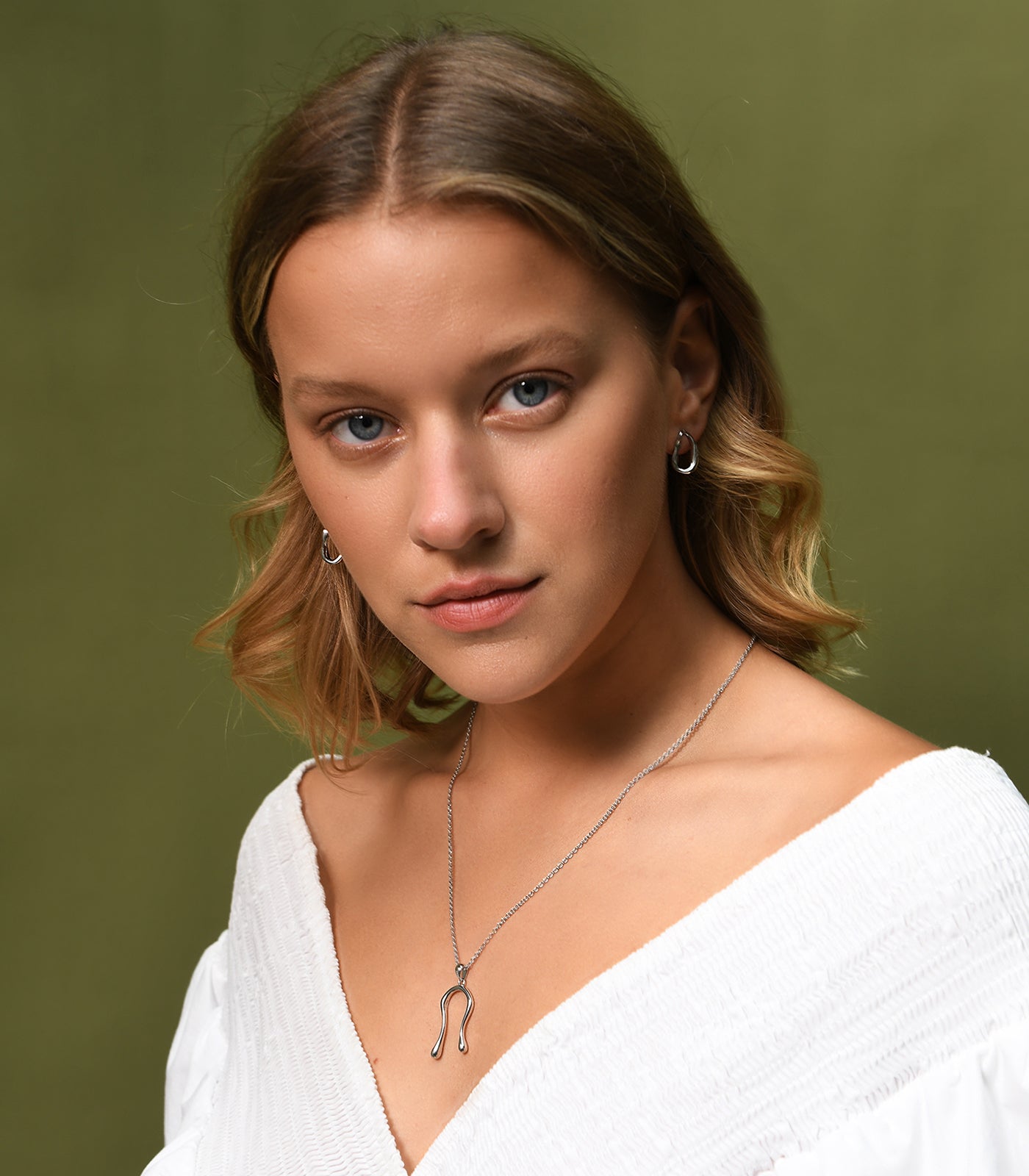 A model wears a sterling silver necklace with a liquid curve pendant resembling water droplets.