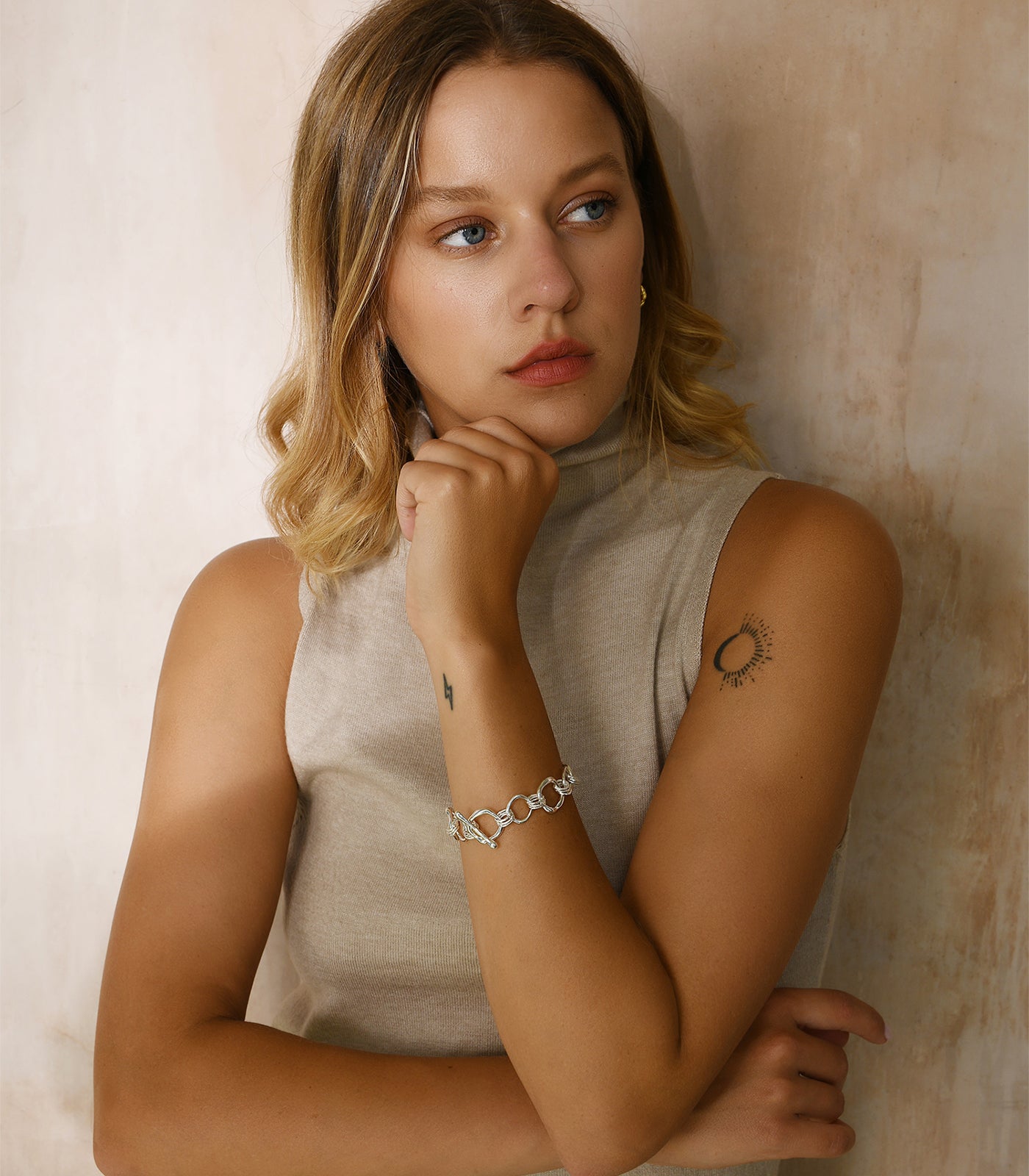 A model wears a sterling silver bracelet, made up of multiple irregularly shaped circle rings linked together.