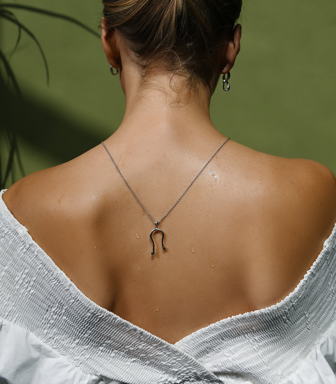 A model wears a sterling silver necklace with a liquid curve pendant which resembles water droplets.