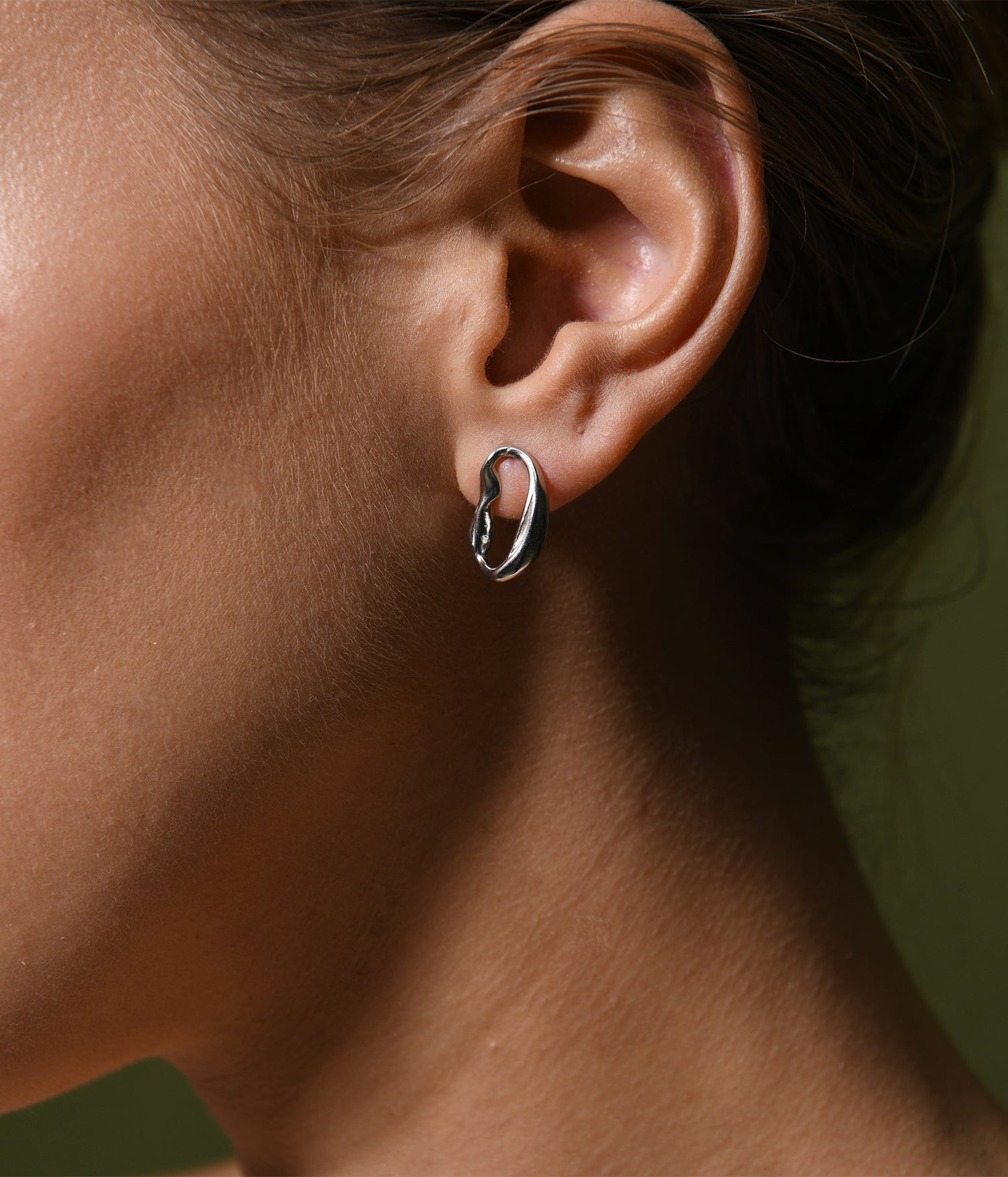 A sterling silver, oval drop hoop earring.