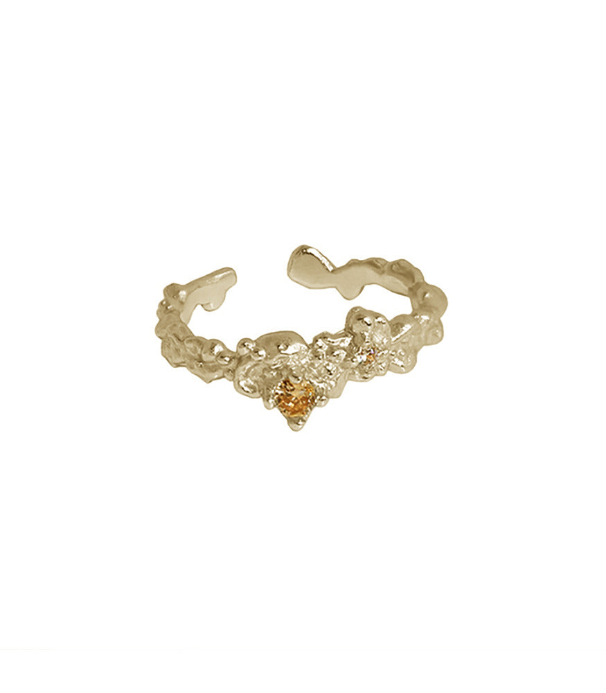 A gold plated ring. The ring is textured with an irregular shaped band and a champagne gold gemstone.