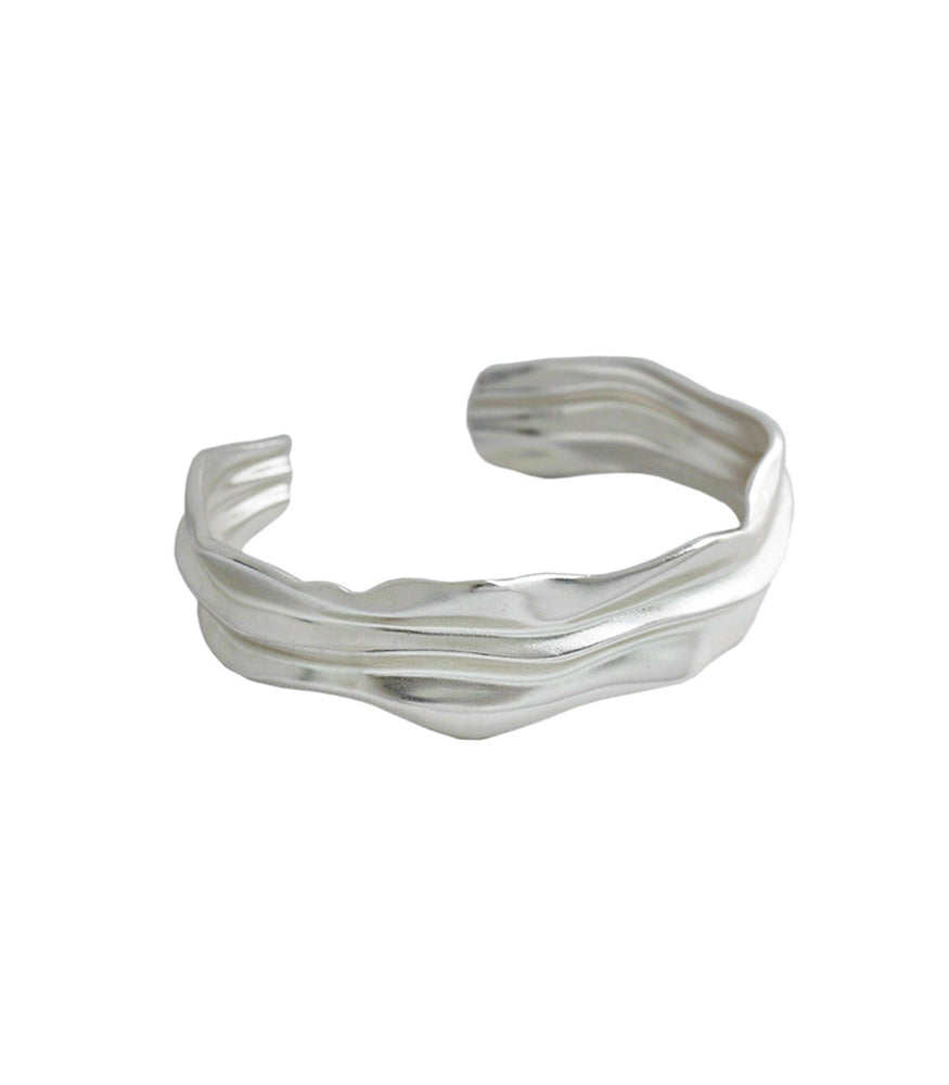 A sterling silver bangle. The bangle is textured and rigid with smooth flowing valleys adding dimension.