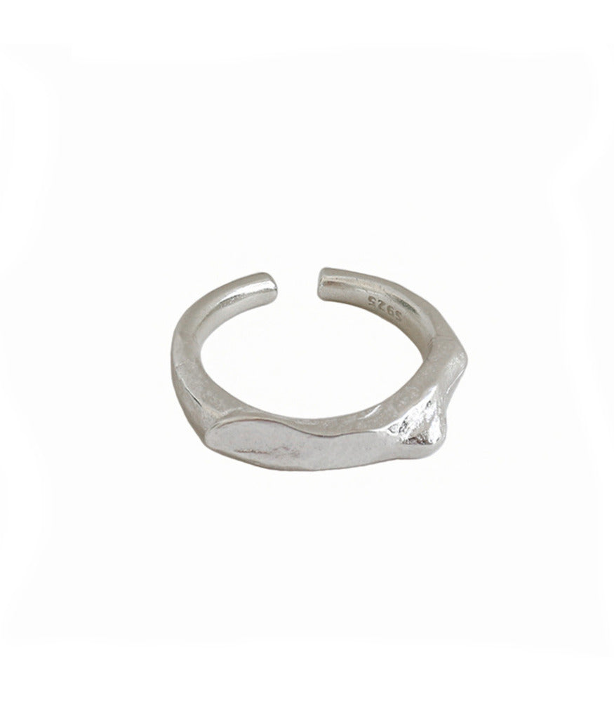 A minimalistic sterling silver ring. The ring has an open band design with an organic rocky texture. 