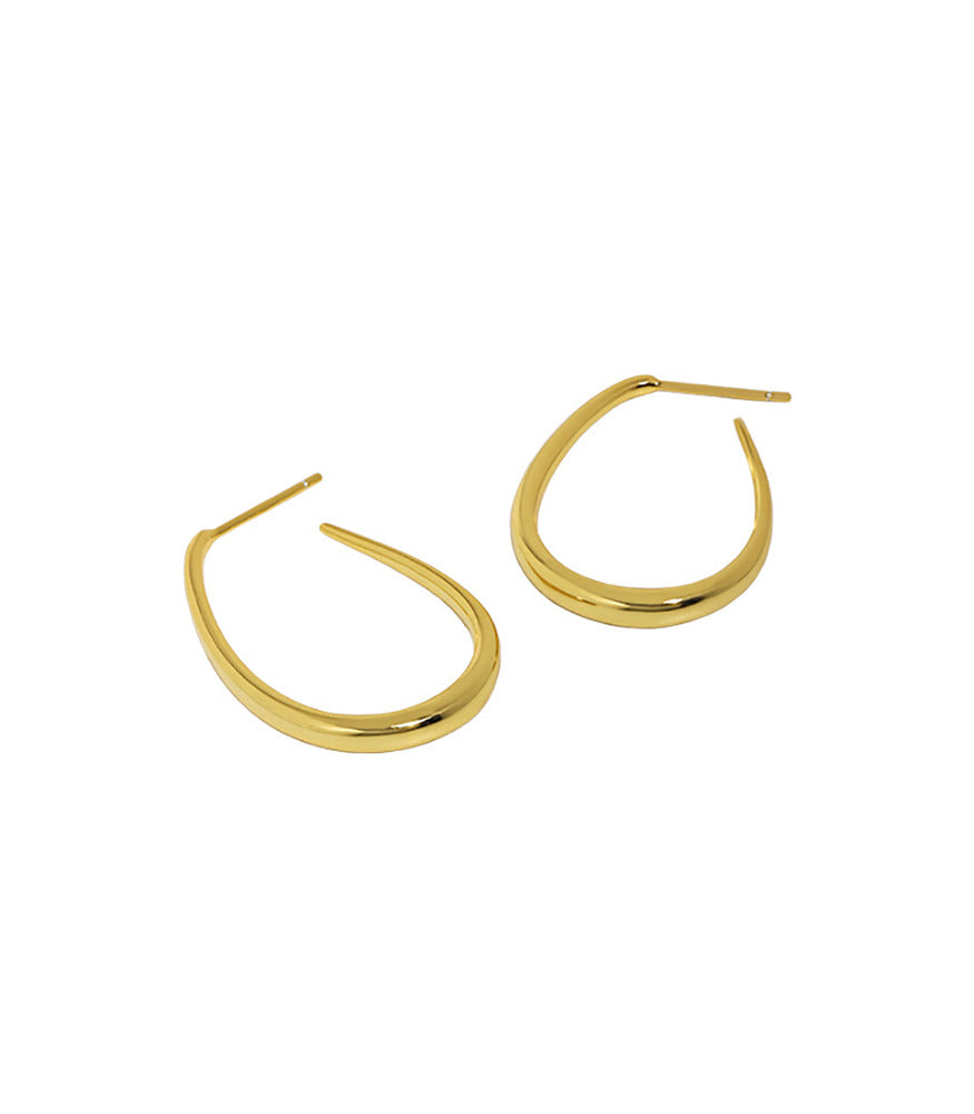 A pair of gold vermeil polished oval hoop earrings in a teardrop shape.