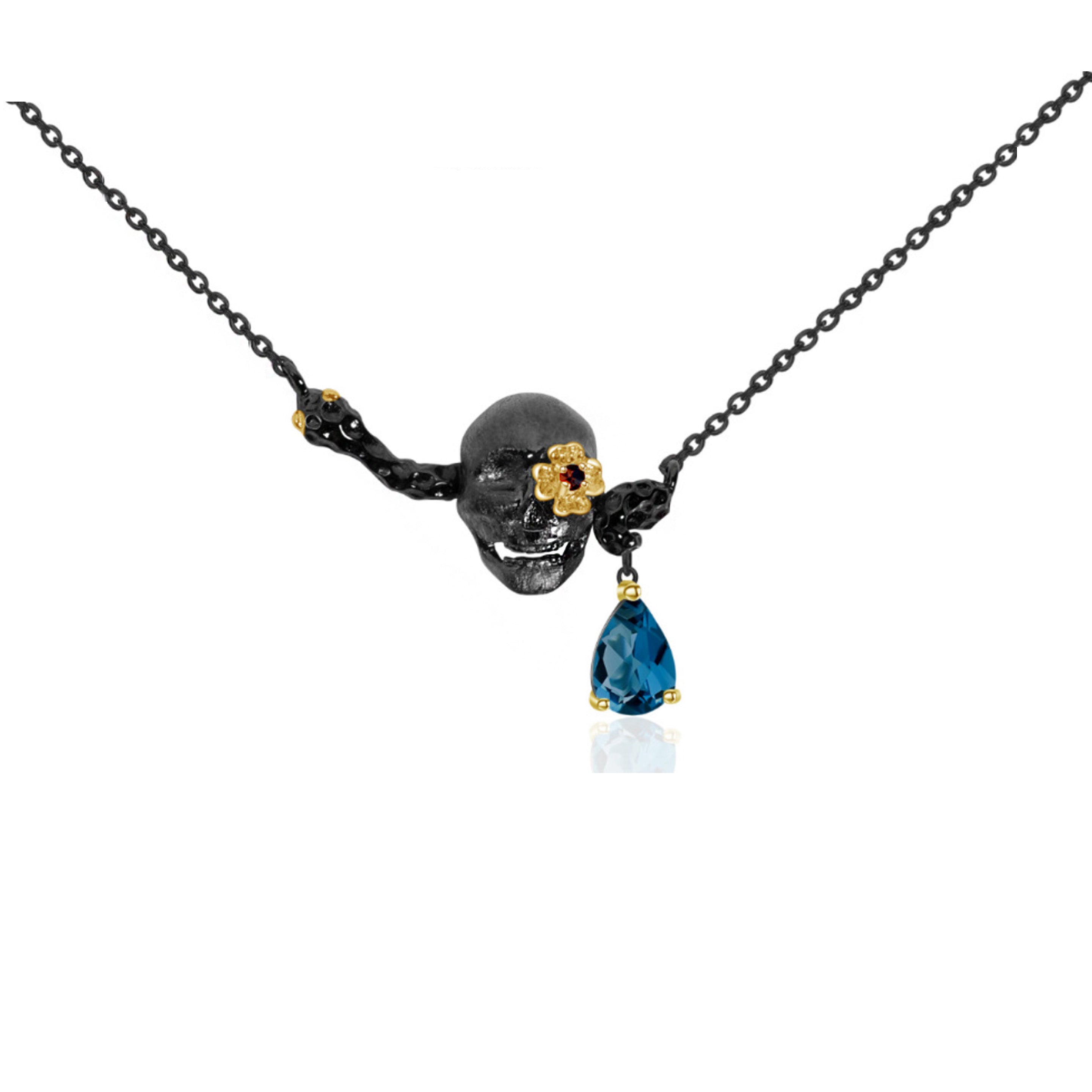 An oxidised black skull necklace. The necklace features a blue topaz and pink ruby stone adding colour to the design.