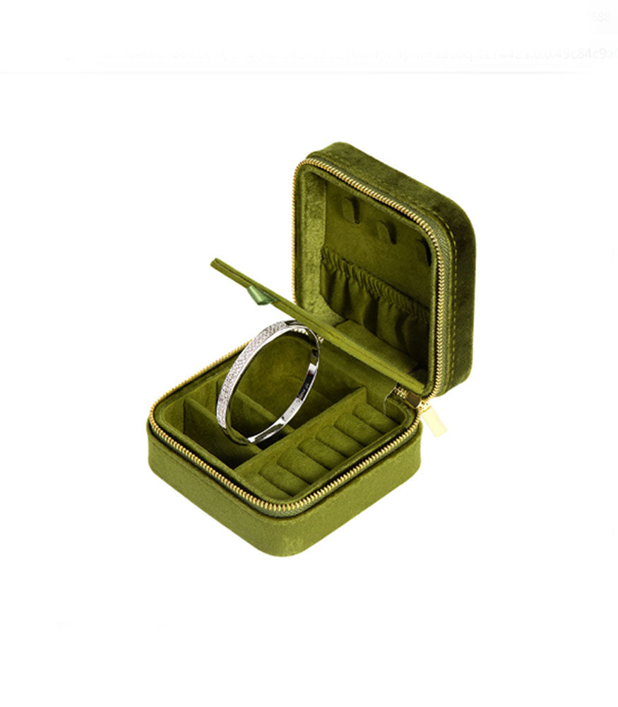 An avocado green velvet jewellery box showing the different compartments for rings, necklaces, bracelets and earrings.